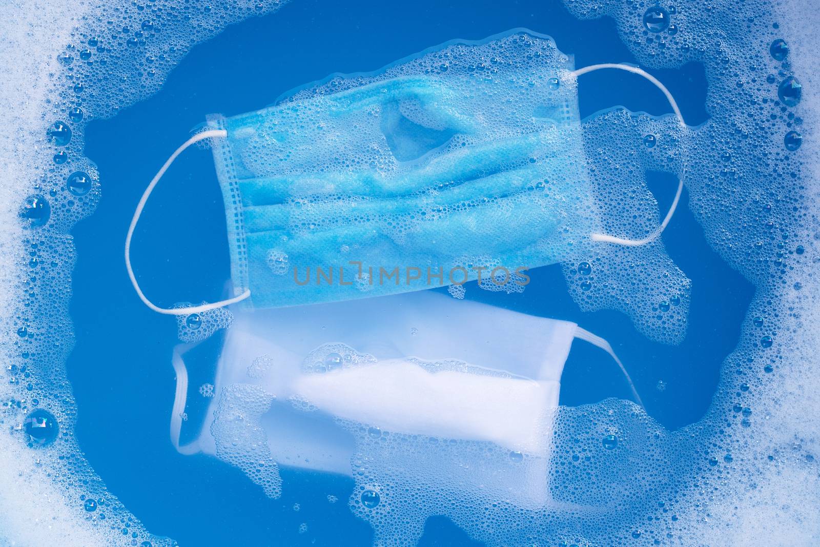 Protective medical mask with cloth mask soak in powder detergent water dissolution before washing. Hygiene coronavirus (Covid-19) protection concept. Top view