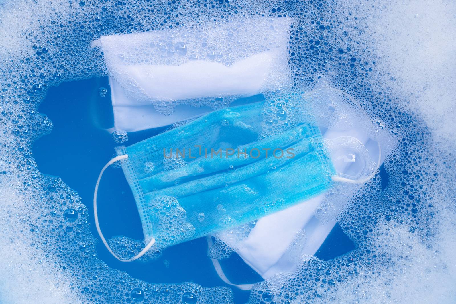 Protective medical mask with cloth masks soak in powder detergent water dissolution before washing. Hygiene coronavirus (Covid-19) protection concept. Top view