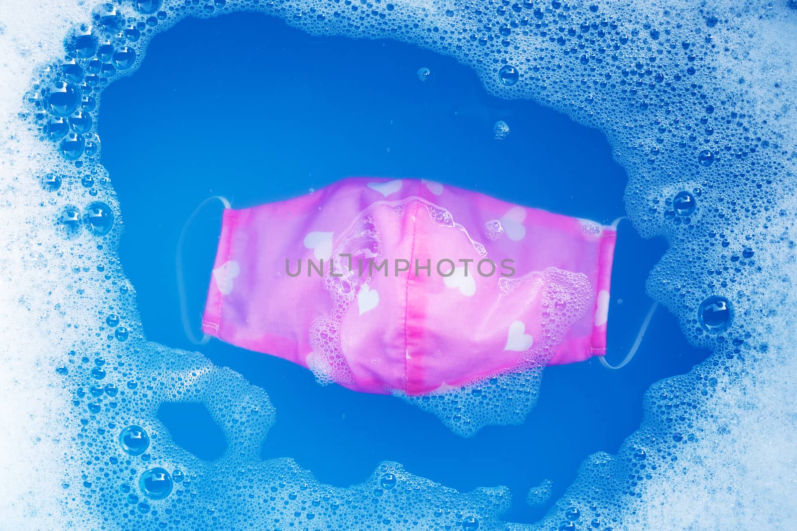 Pink cloth masks soak in powder detergent water dissolution befo by Bowonpat