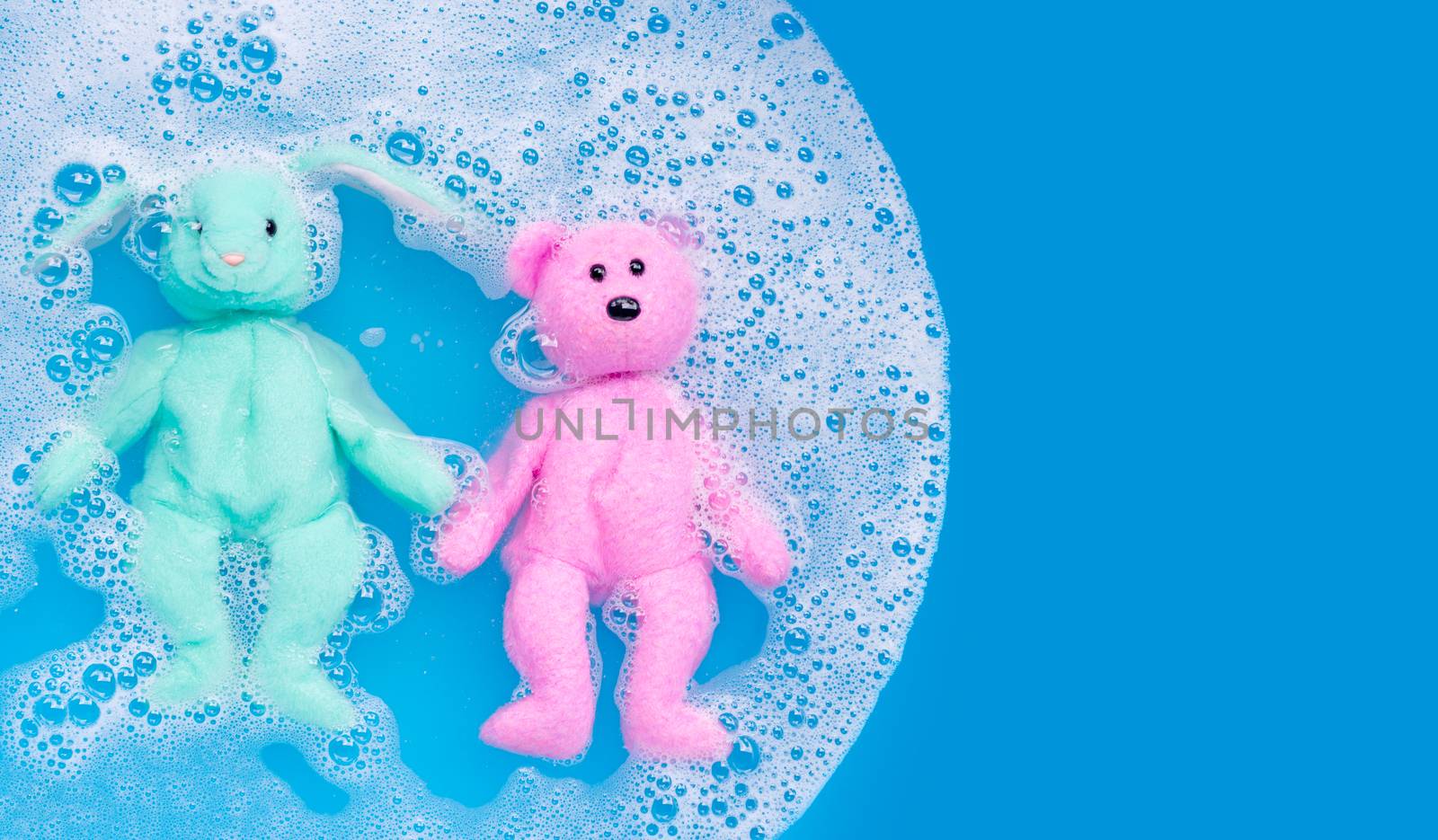 Soak rabbit doll with  toy teddy bear in laundry detergent water dissolution before washing.  Laundry concept, Top view