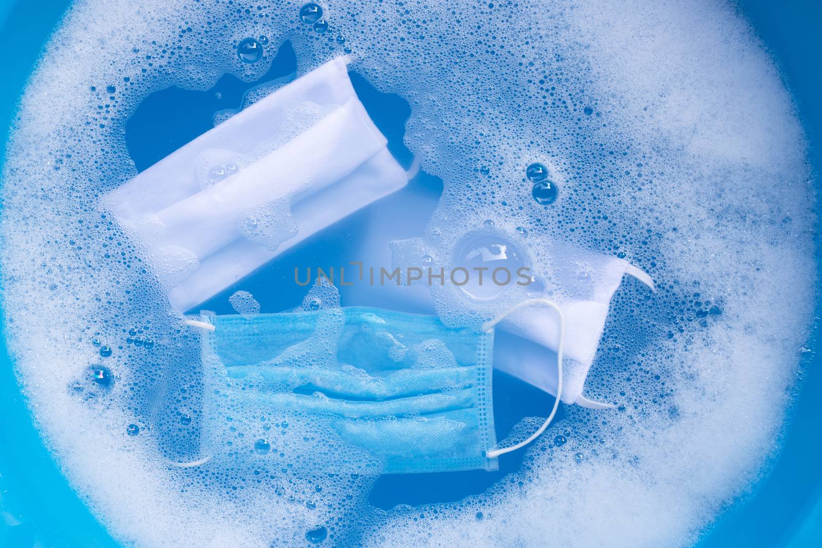 Protective medical mask with cloth masks soak in powder detergent water dissolution before washing. Hygiene coronavirus (Covid-19) protection concept. Top view