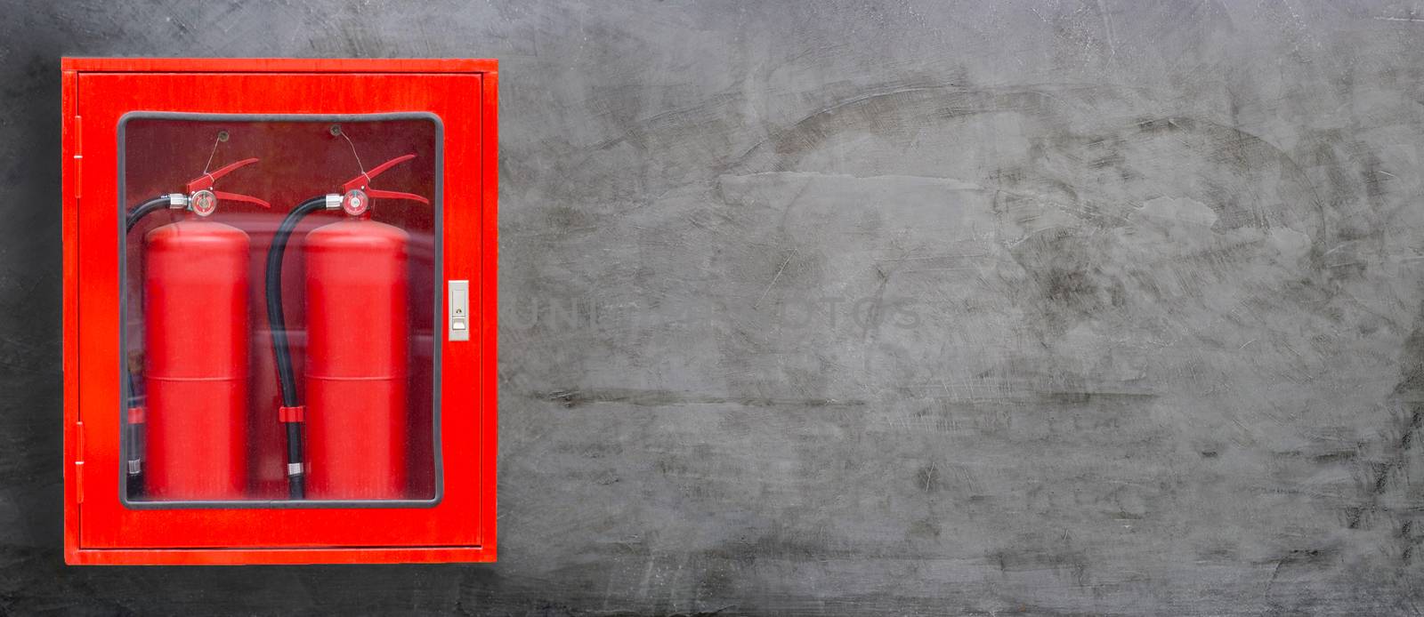 Fire Extinguisher in red cabinet on concrete wall background. Copy space