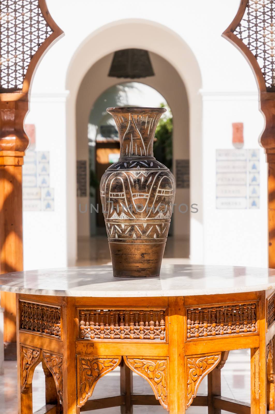 A big egyptian vase on a wood and marble arabian table