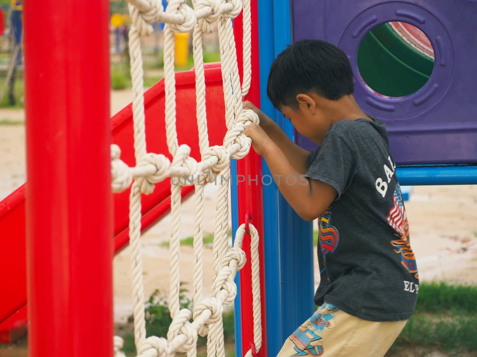 Boy climbing rope ladder In the playground.