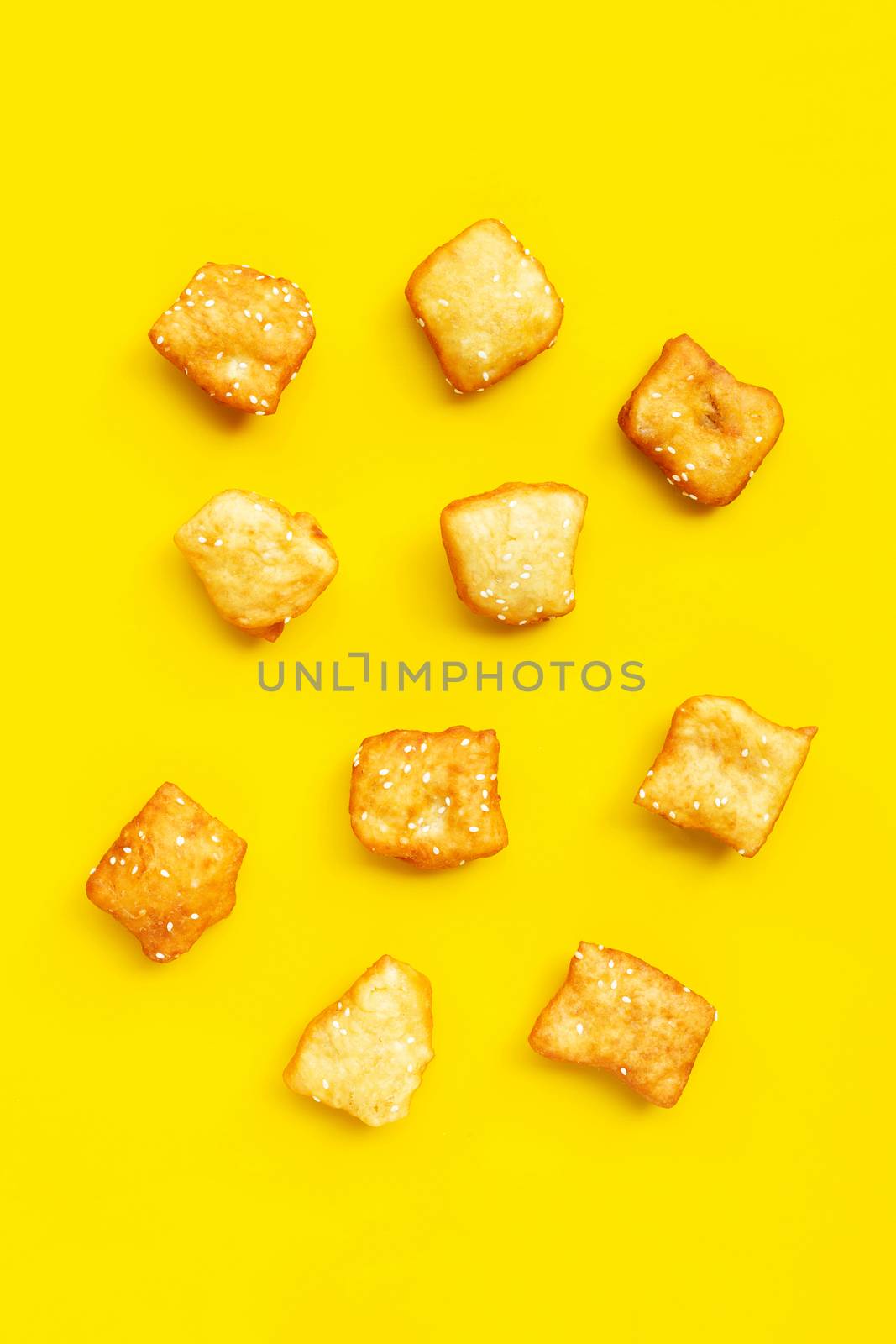 Chinese deep fried dough sticks with white sesame seeds on yellow background.