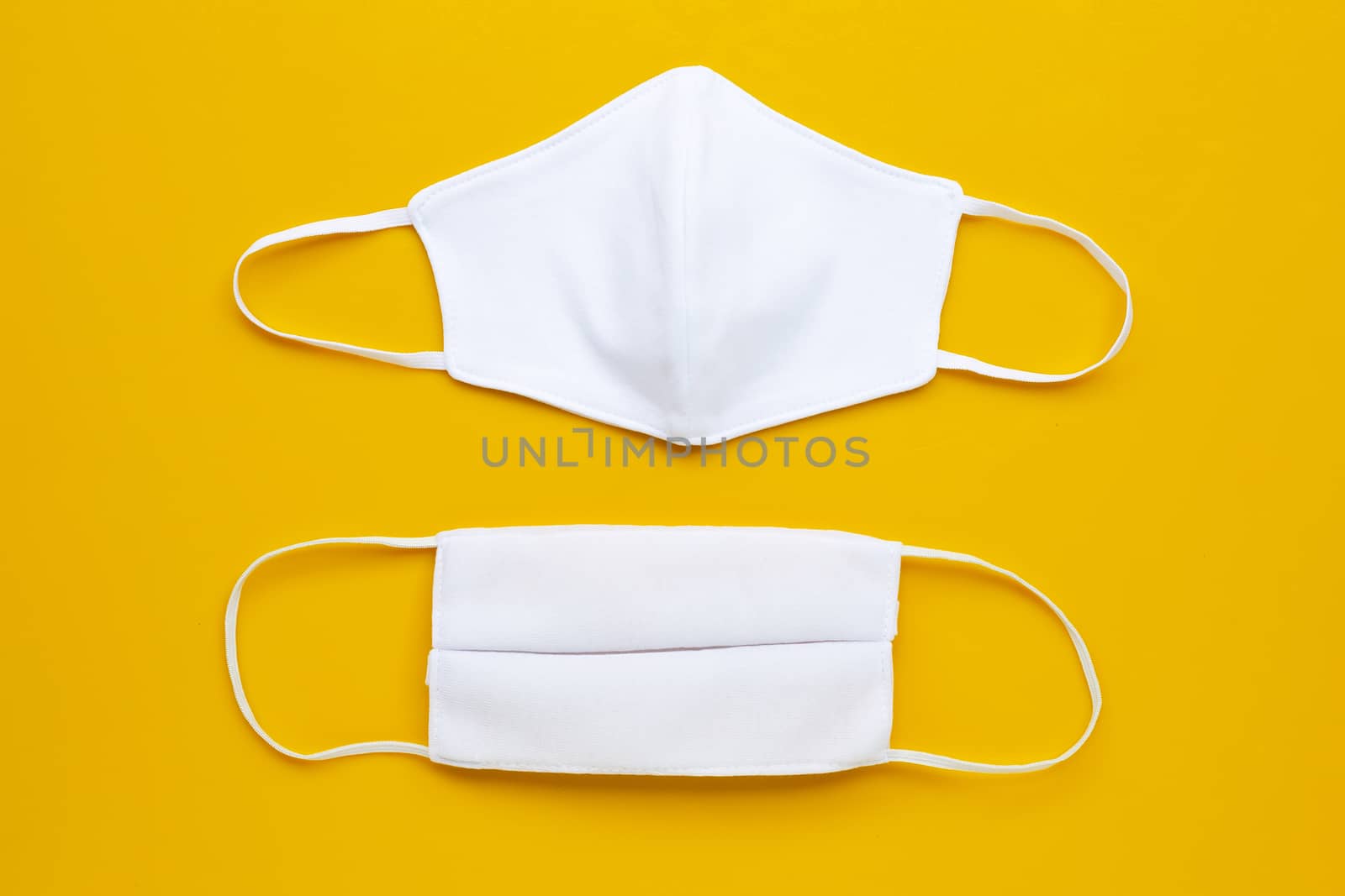  Handmade white cloth masks on cream yellow background.  Top view