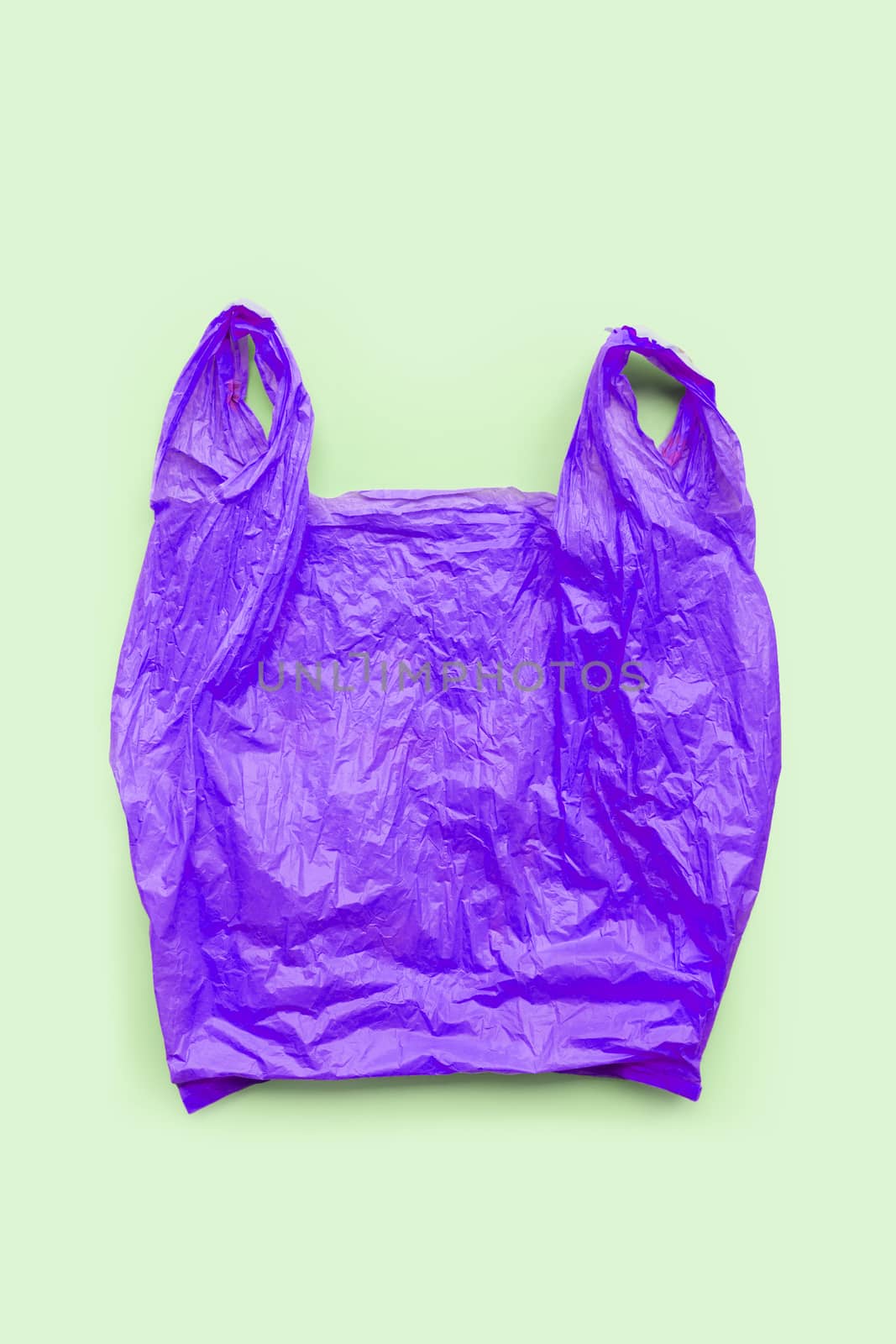Purple plastic bag on green background. Environment pollution concept. Top view