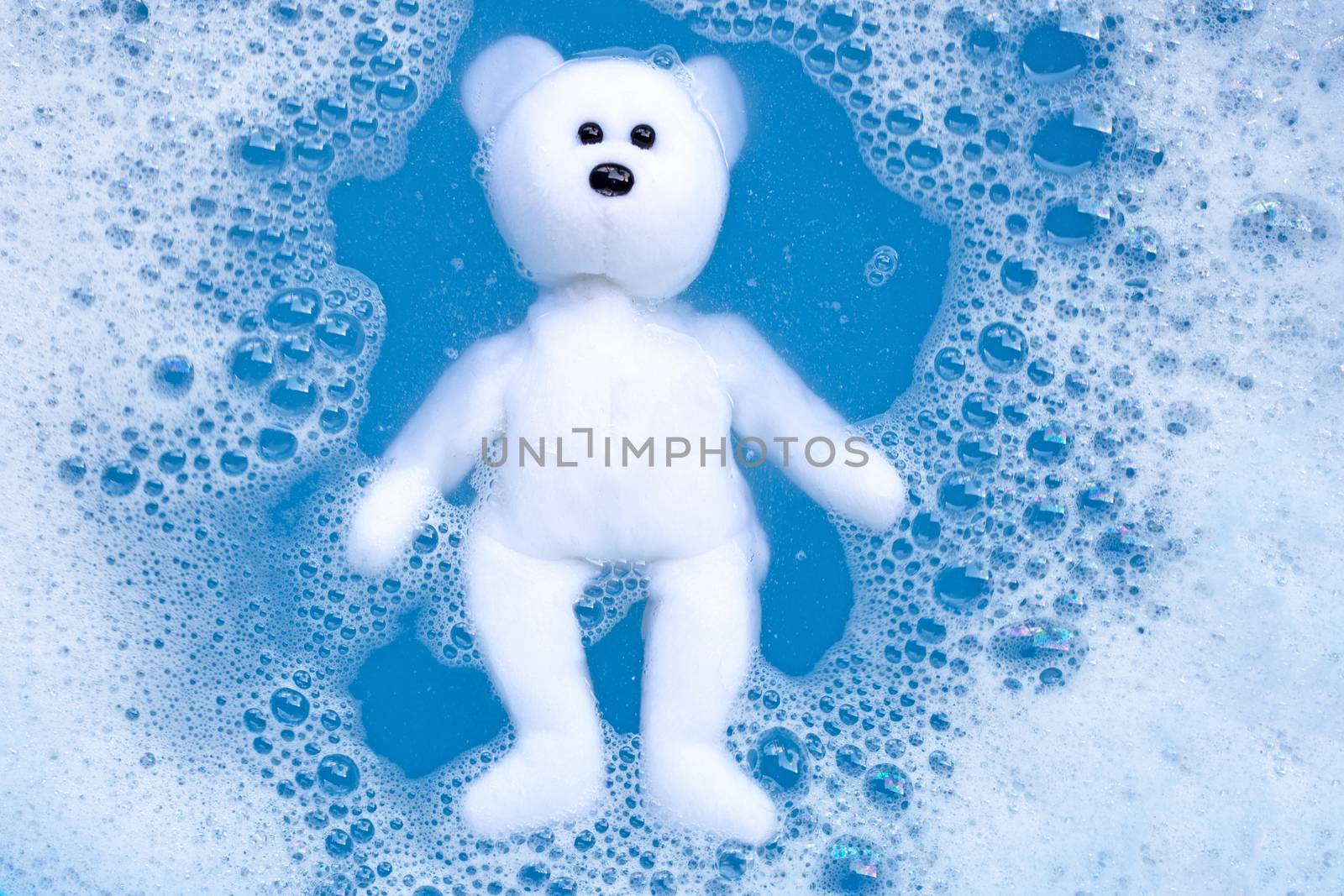 Soaking bear toy in laundry detergent water dissolution before washing. Laundry concept, Top view