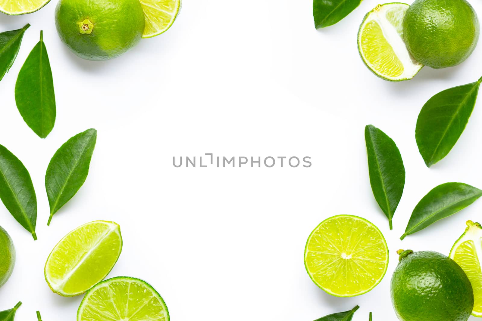 Frame made of fresh limes with green leaves on white background. Copy space