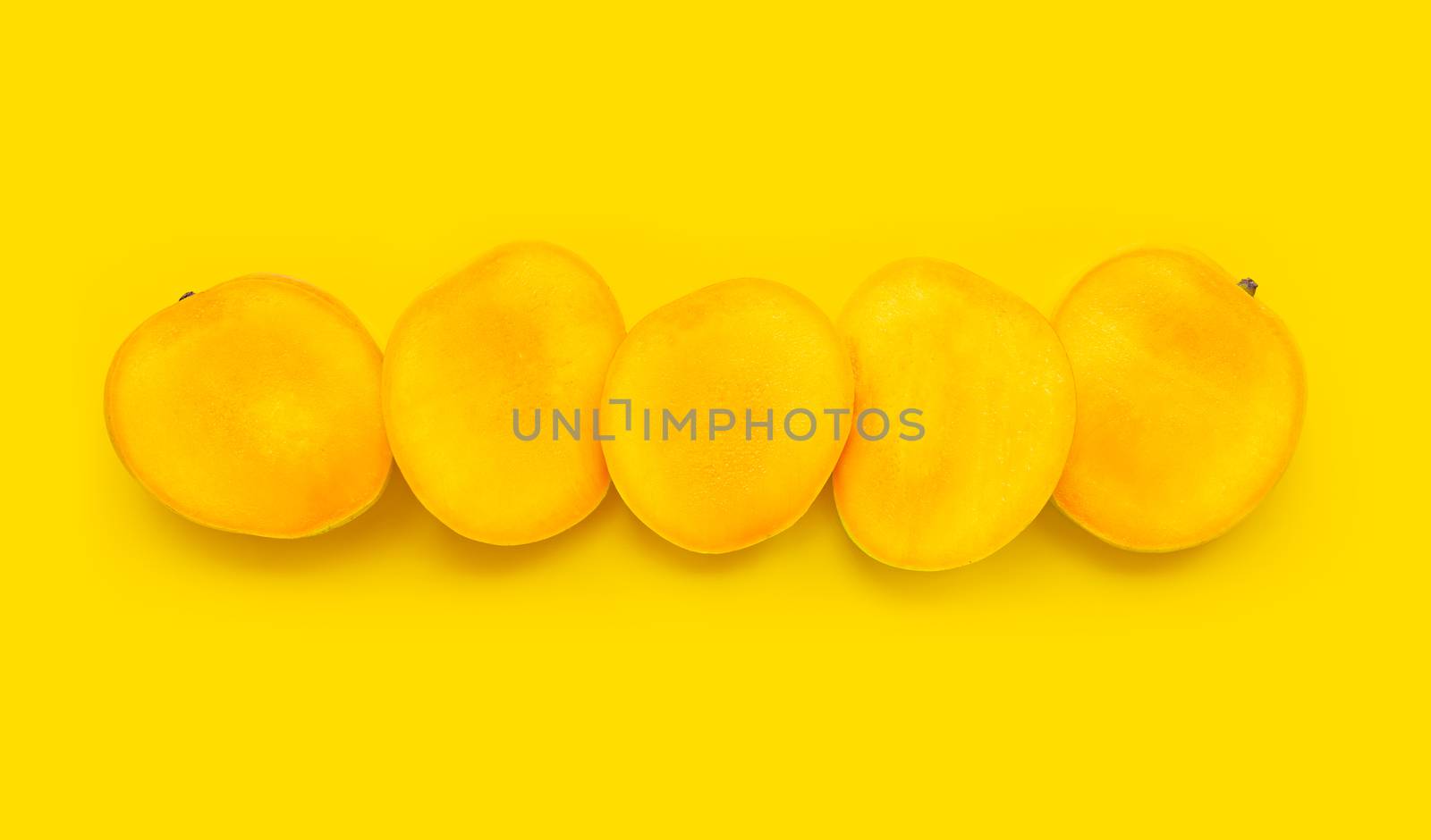Tropical fruit, Mango slices on yellow background. Top view
