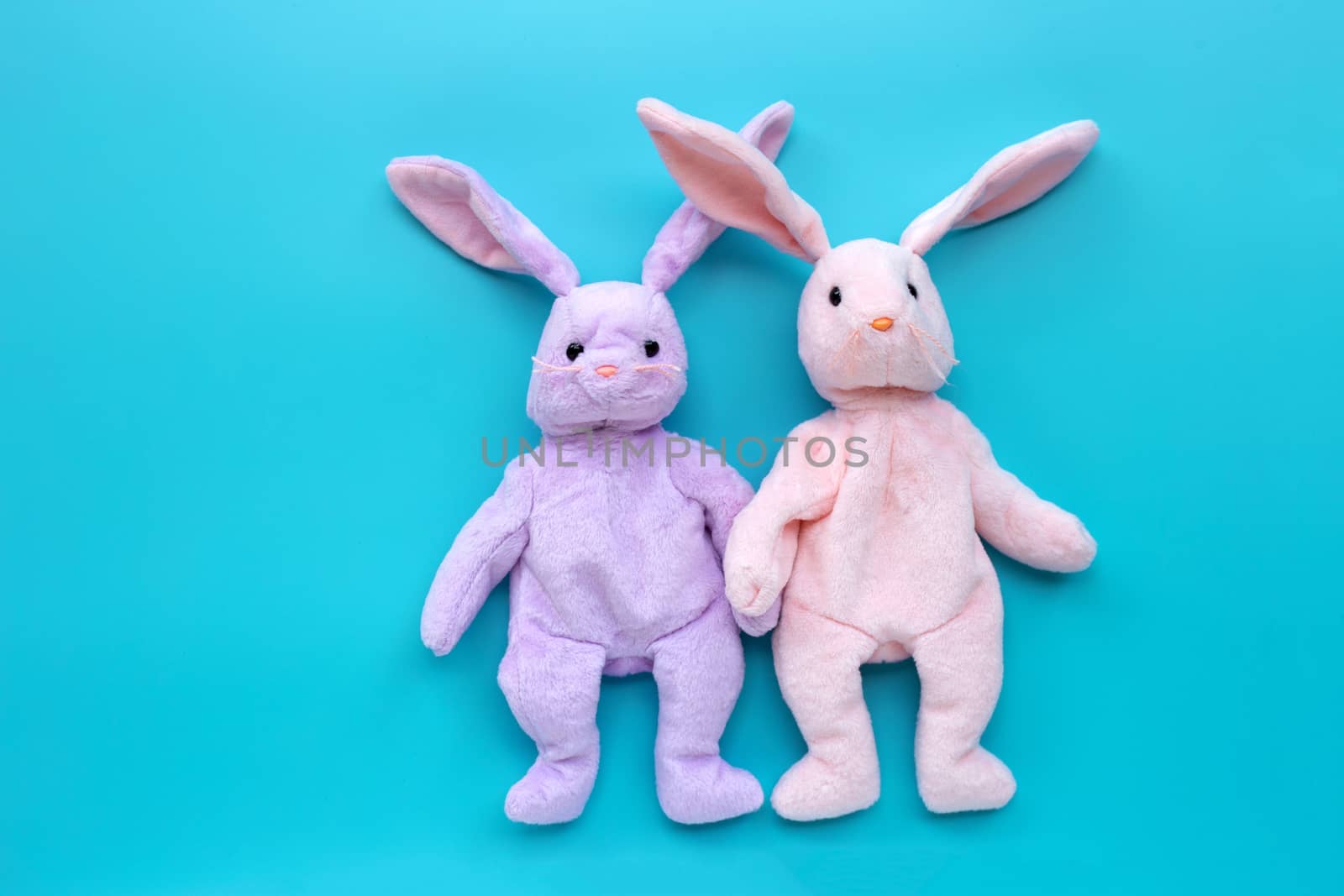 Rabbit toy couple on blue background. Copy space