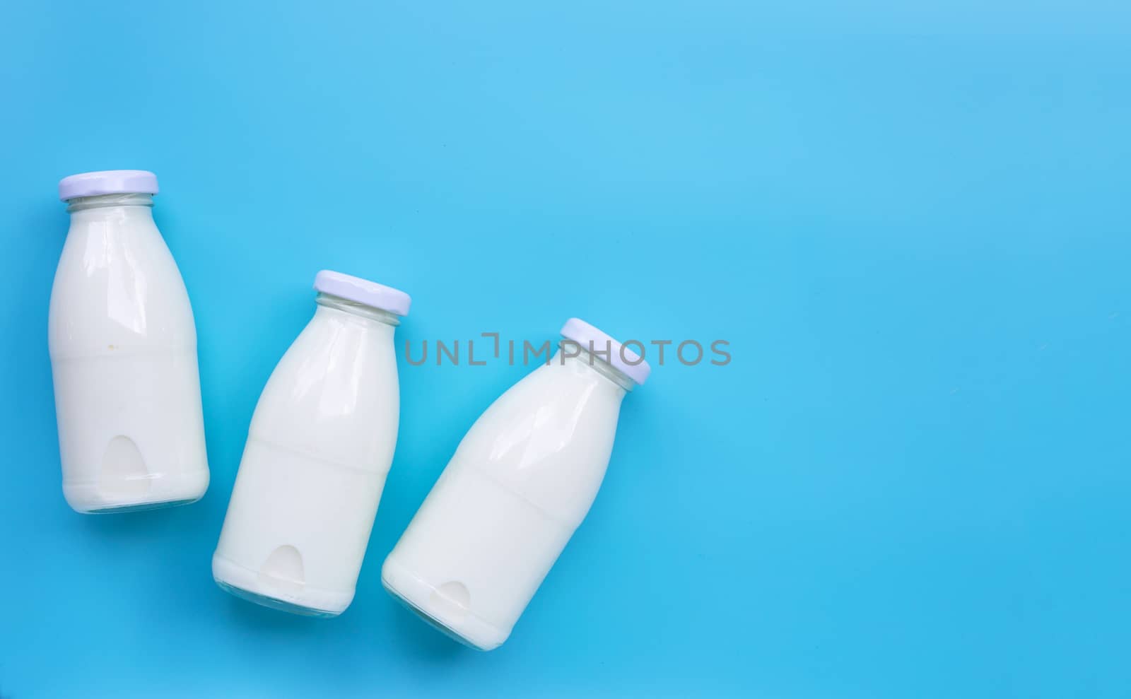 Milk bottles on blue background.  by Bowonpat