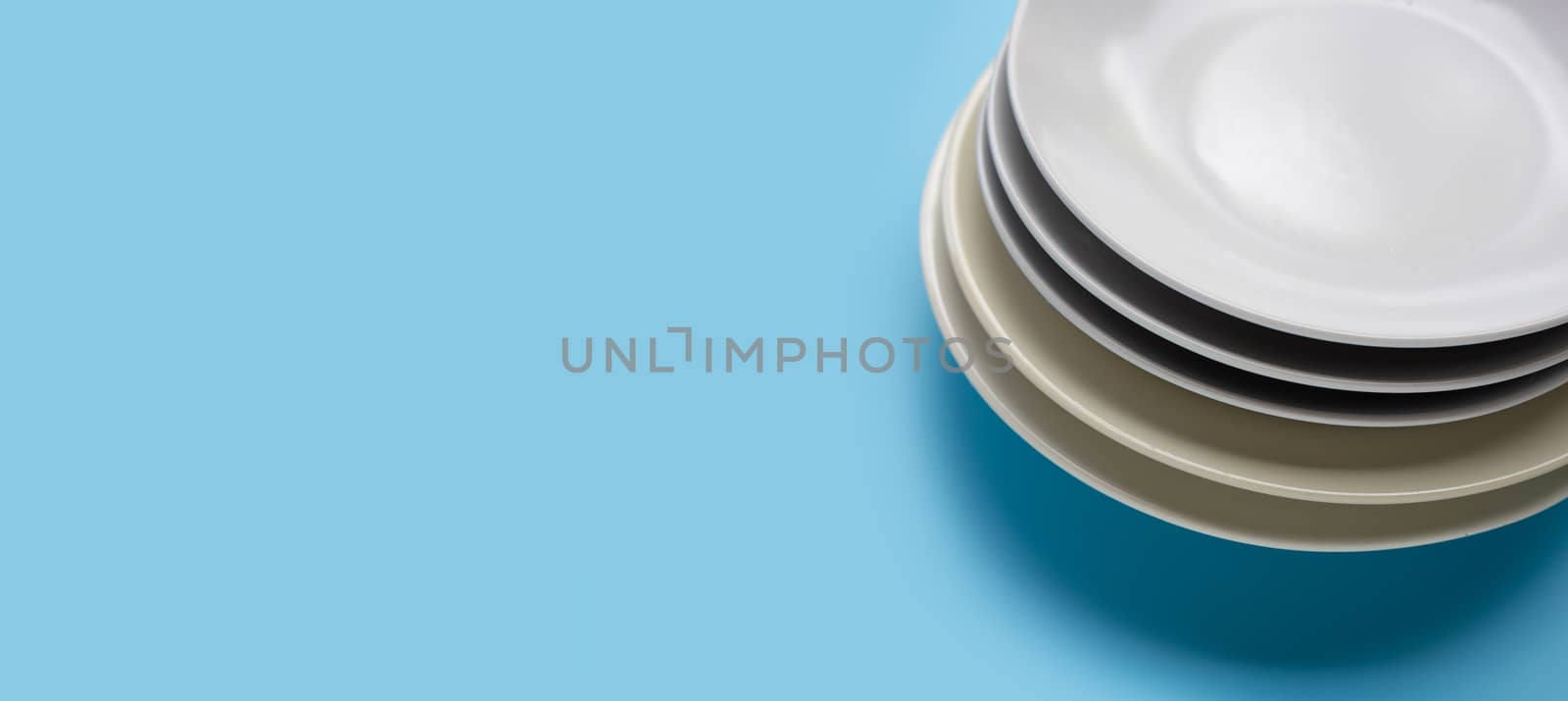Stack of dishes on blue background. by Bowonpat