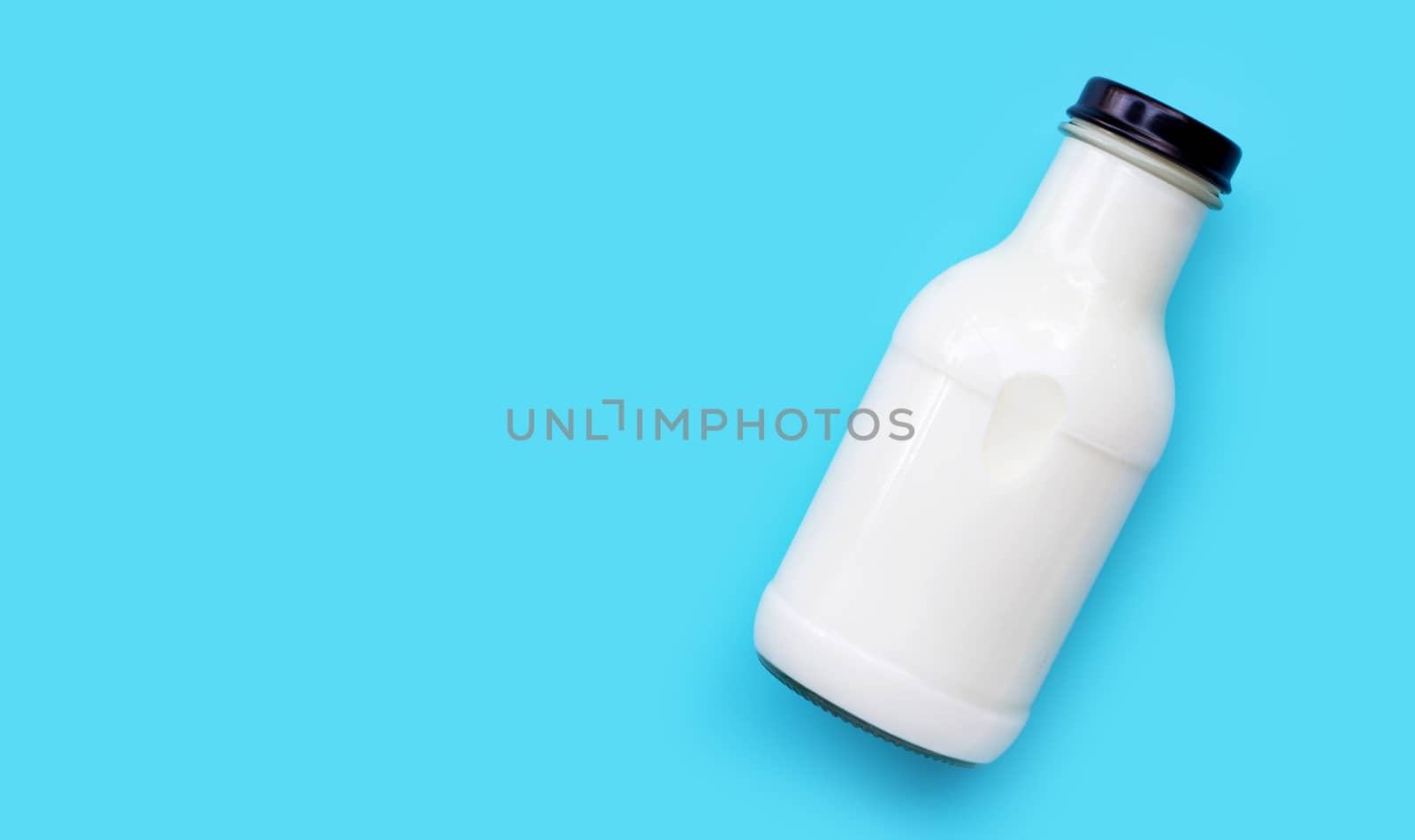 Milk bottle on blue background. Copy space