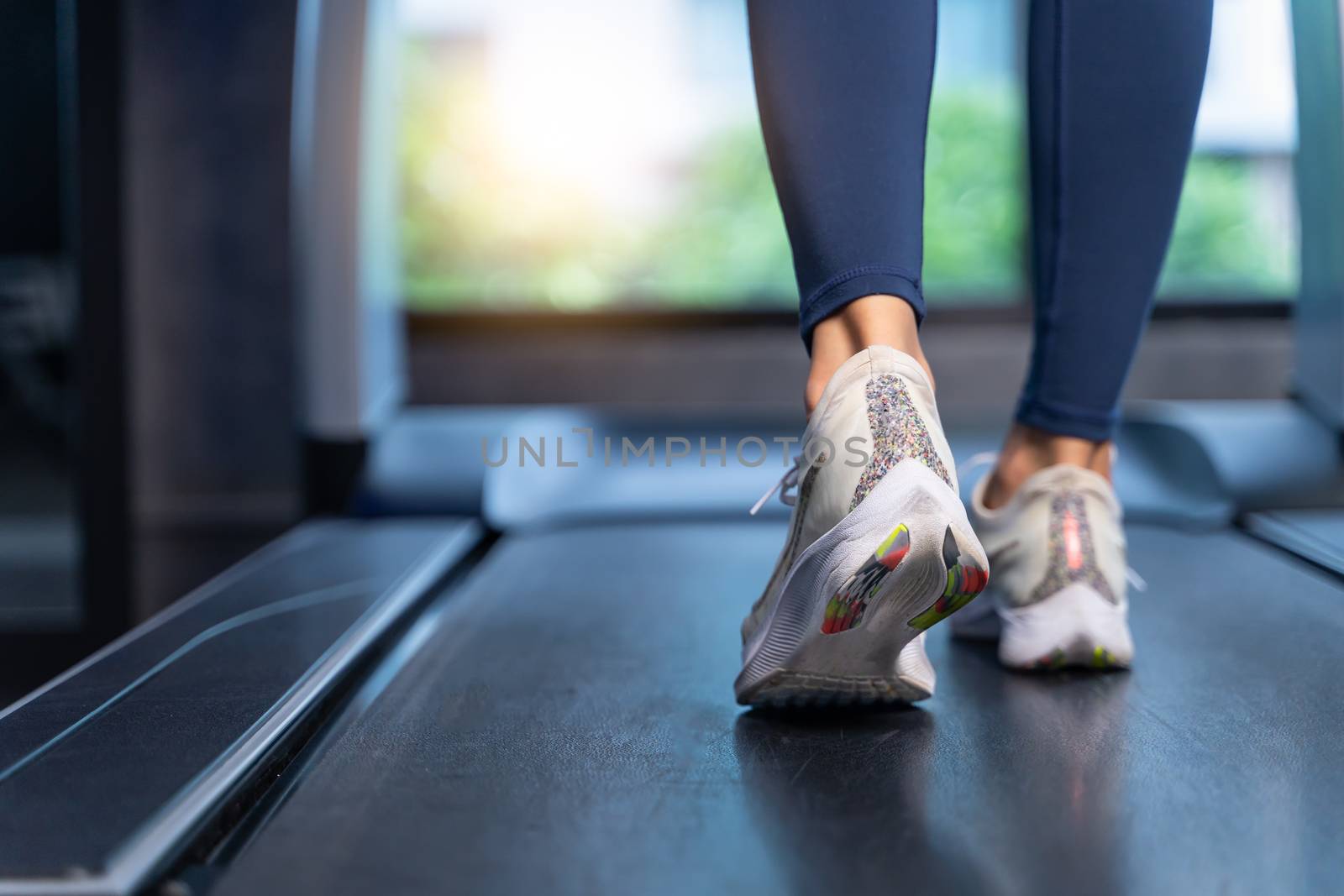 Close-up Women's feet are running on a treadmill at the gym. Women are stretching, warming up before cardio in sport and healthy concept