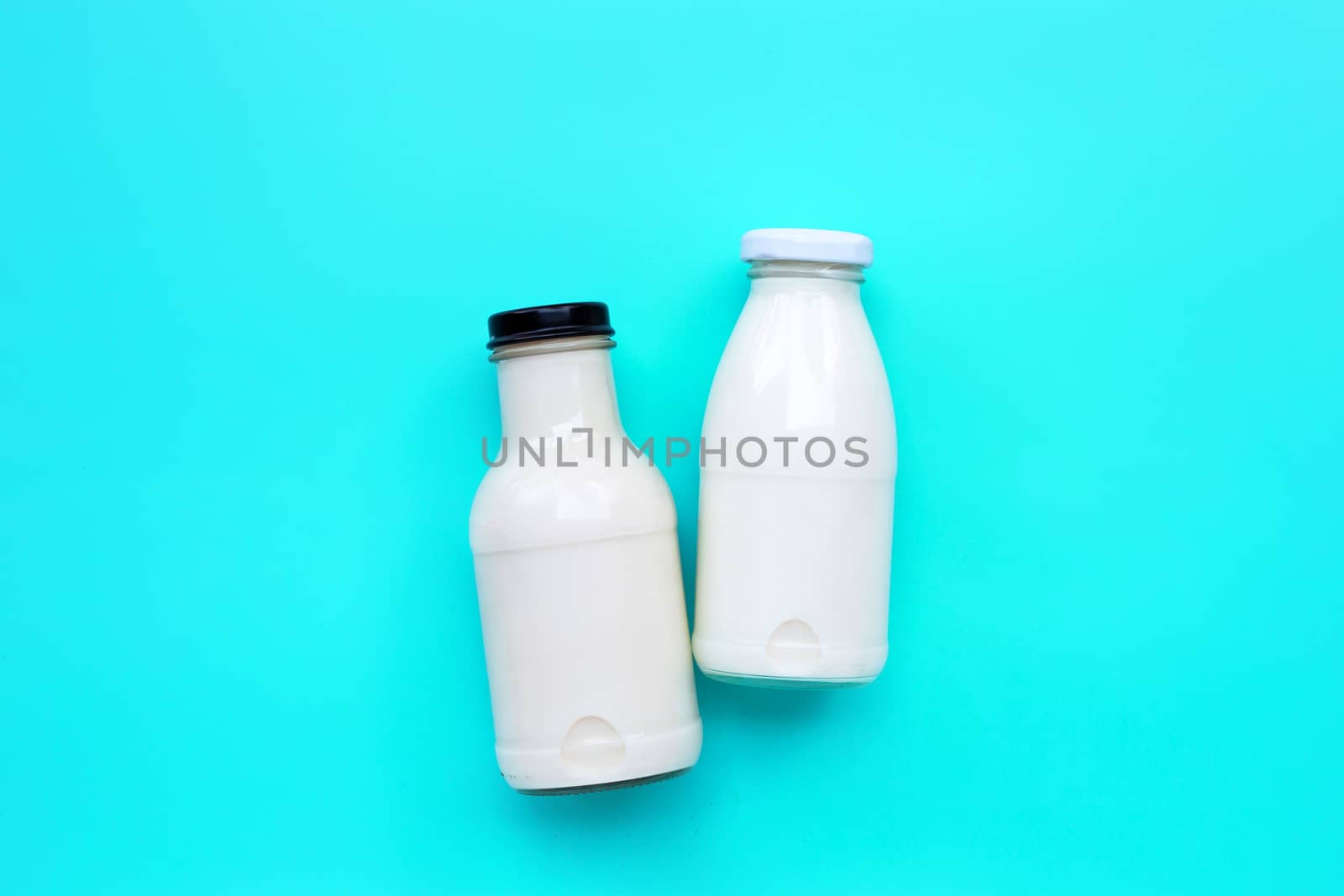 Milk bottle on blue green background. Copy space