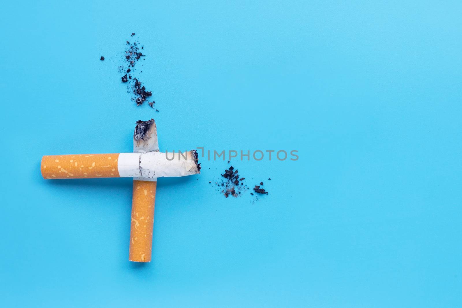 Cigarette butts and ashes on blue background. Copy space