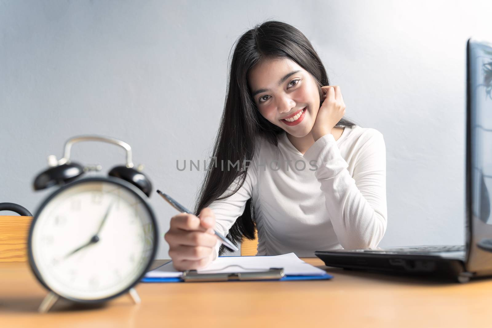 Work from home during the outbreak of the virus. Asian women sitting and working at home or online meeting, video conference and Writing data in a book in business concept at home office