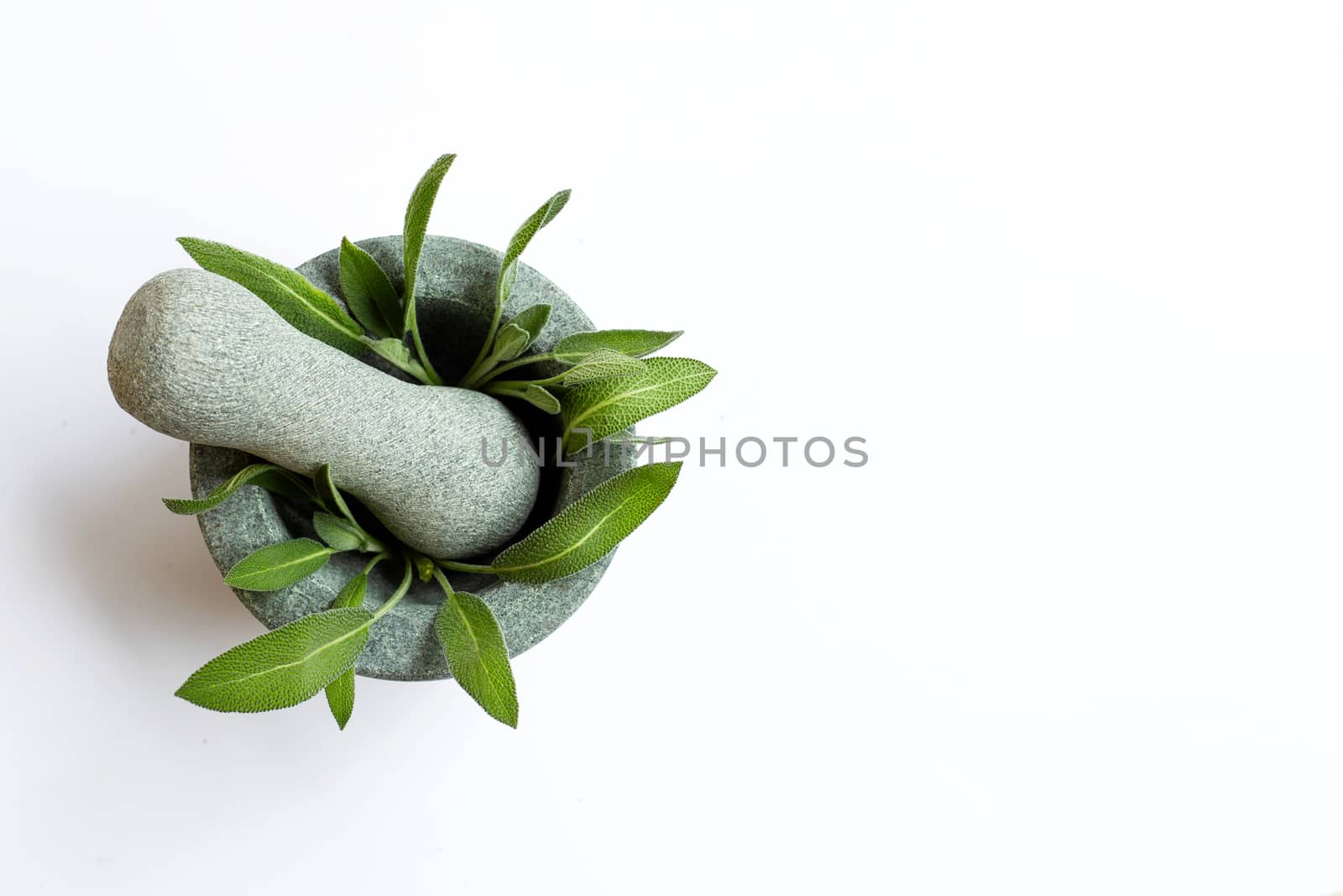 Sage leaves in stone mortar and pestle on white background. Top view