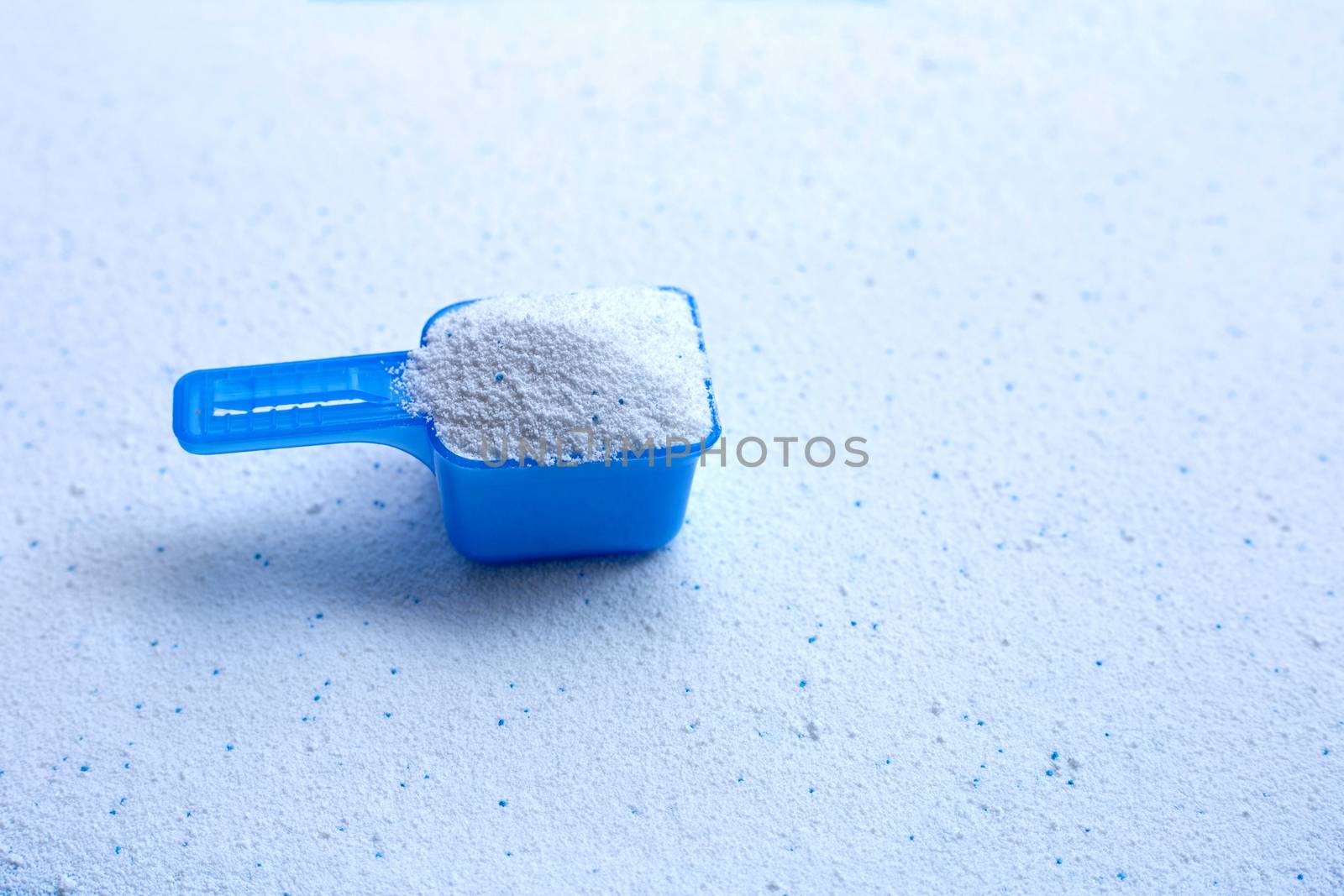 Blue measuring scoop with laundry powder. Copy space