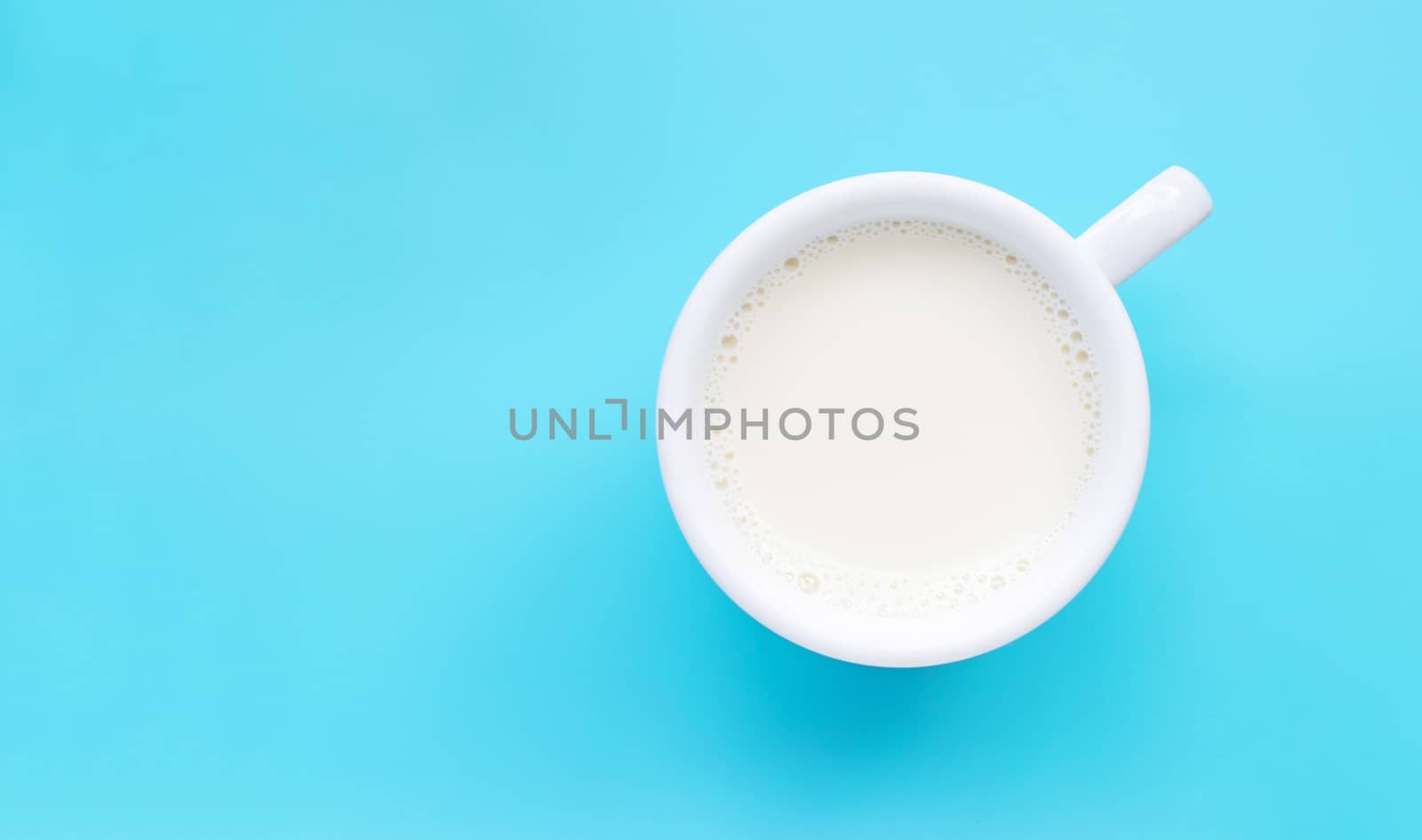 Cup of milk on blue background. Copy space