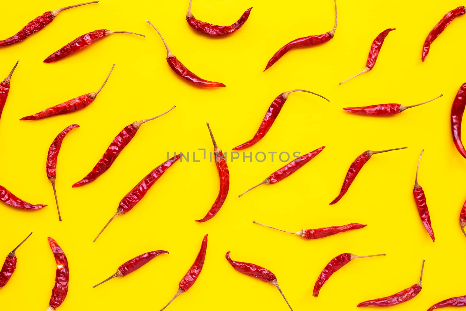 Dry red hot chili peppers on yellow background. Top view