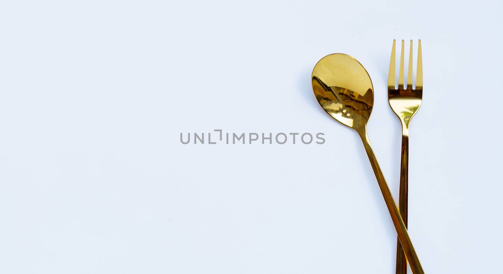 Golden spoon and fork on white background. Copy space