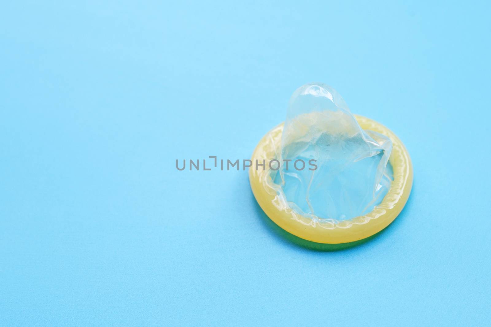 Condom on blue background with copy space. Save sex concept