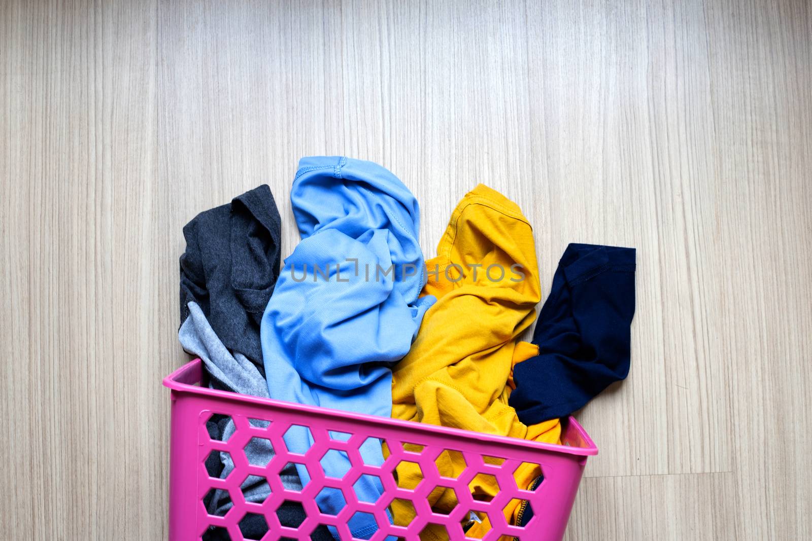 Clothes in pink plastic laundry basket. Top view