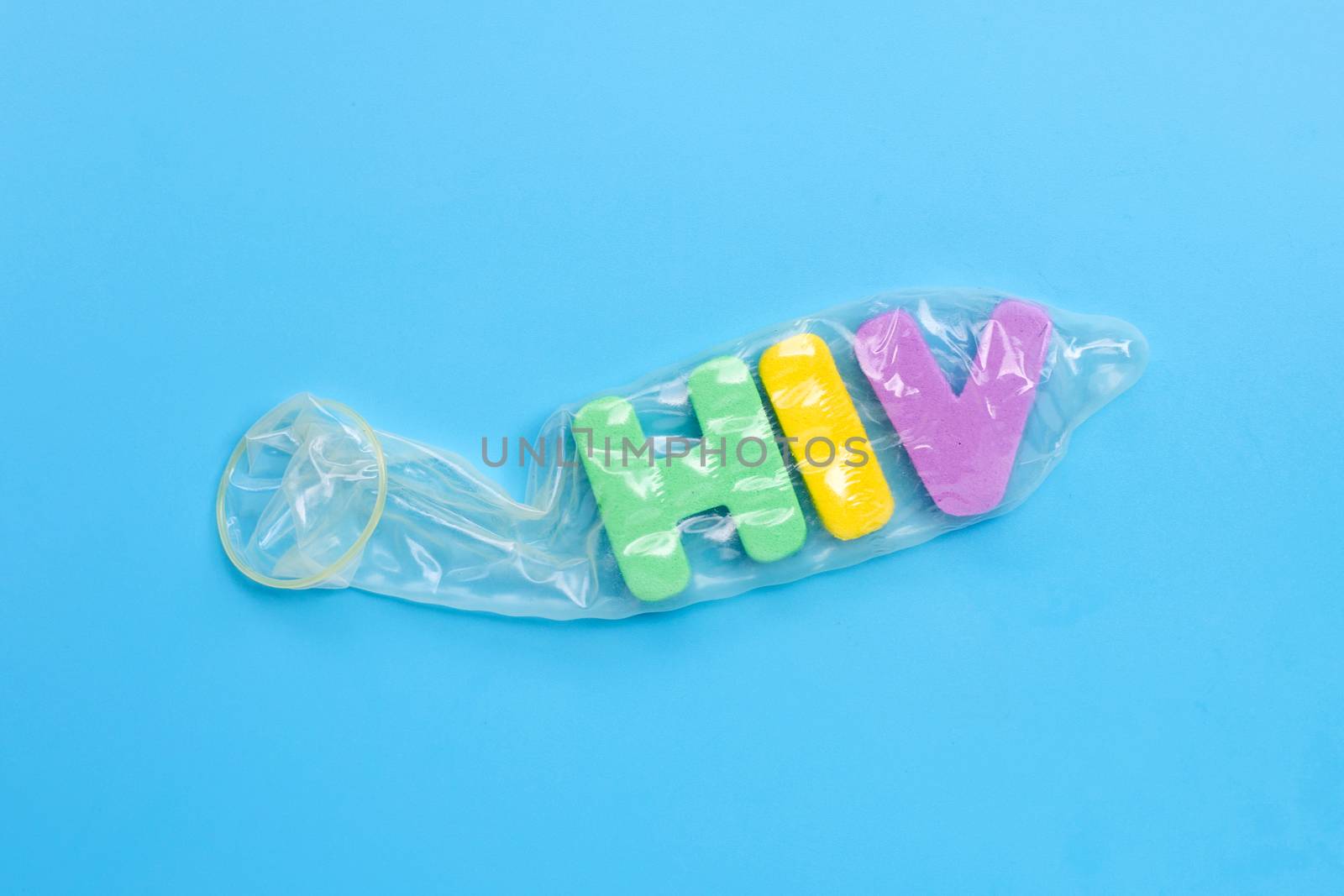 Condom with "HIV" alphabet on white blue background. Copy space