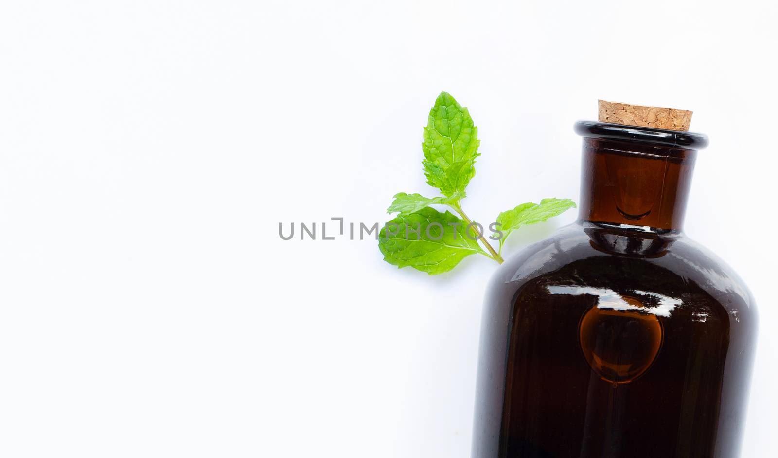 Essential oil bottle with fresh mint leaves on white background. 