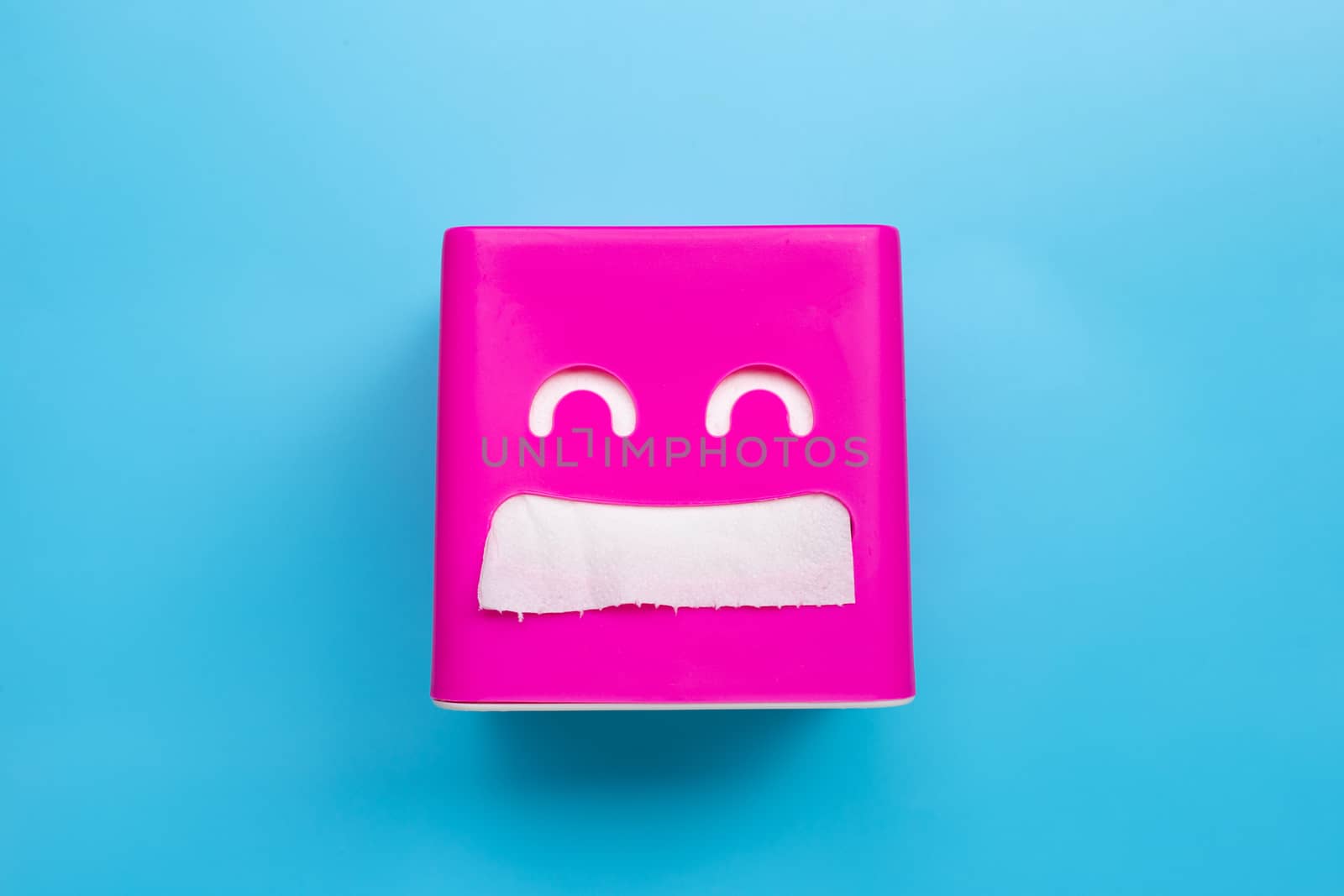 Pink tissue paper box on blue background. Copy space