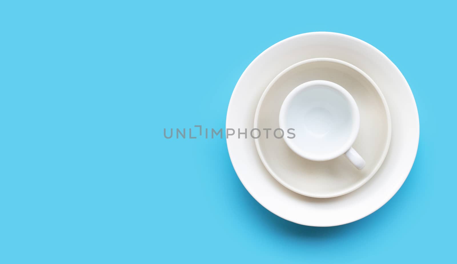 Stack of dish, bowl and cup on blue background. Copy space