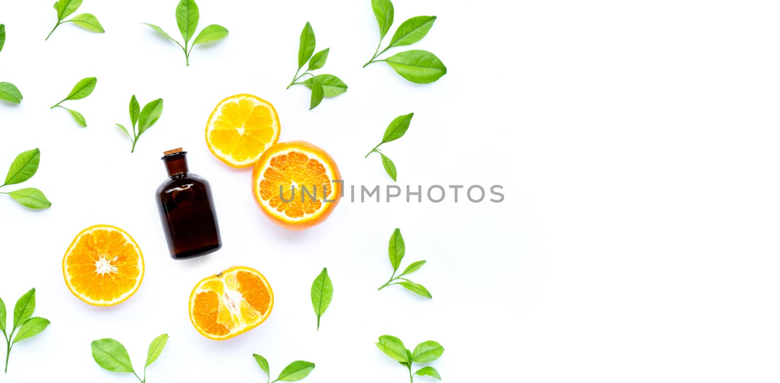 Fresh orange fruit and leaves with essential oil bottle on white background. Copy space