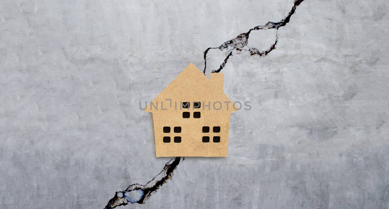 Miniature house on cracked cement wall texture background. Top view