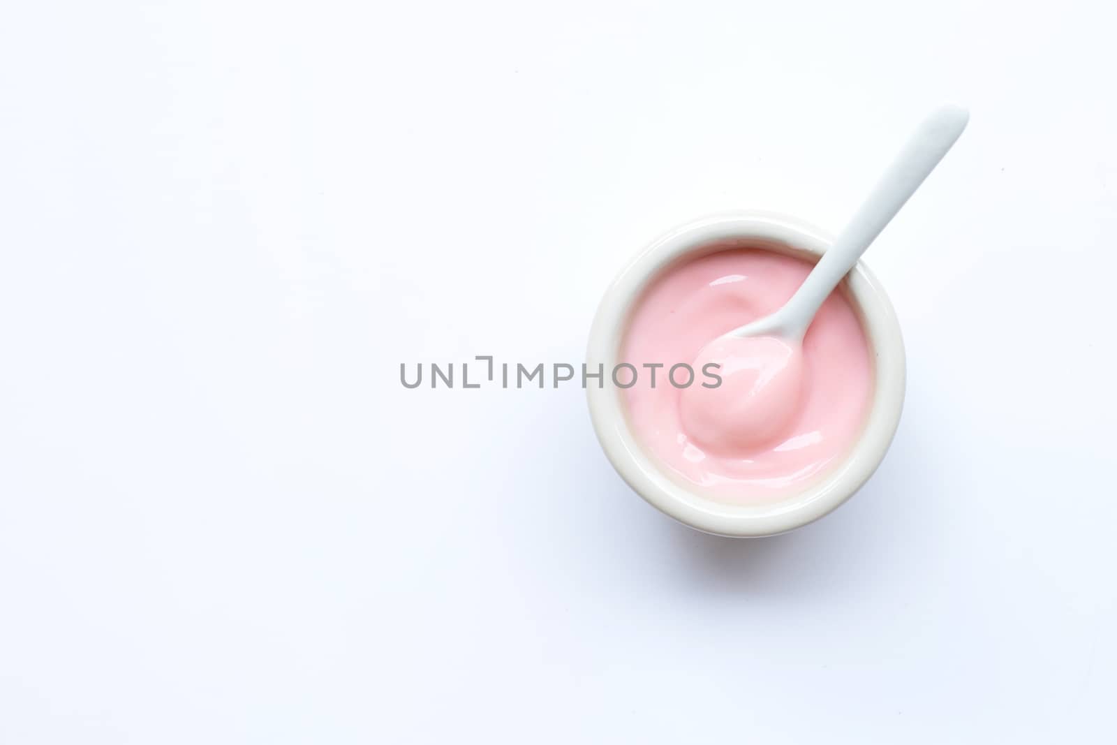 Ceramic bowl of  pink strawberry yogurt on white background.