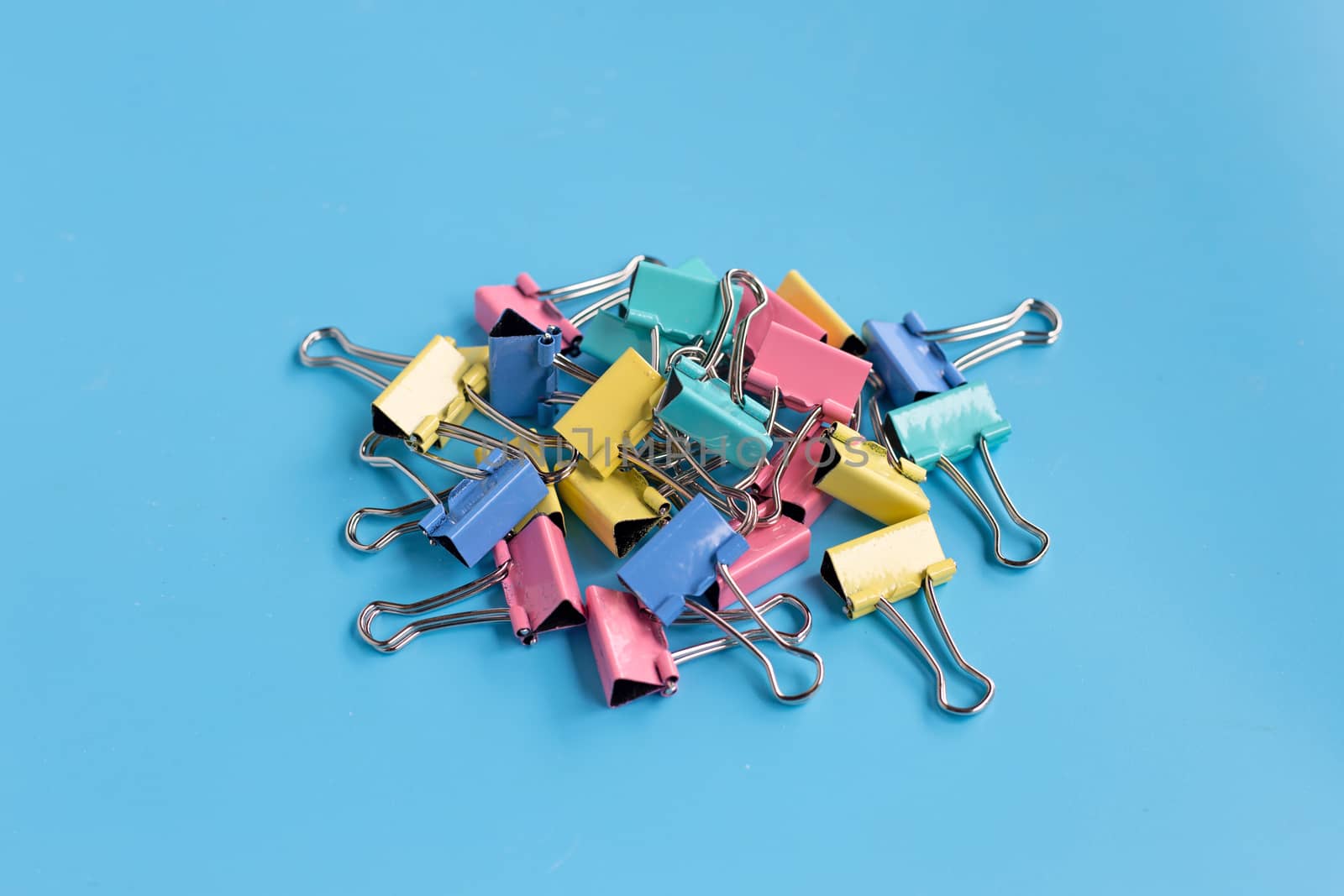 Colorful office paper clips on blue background.