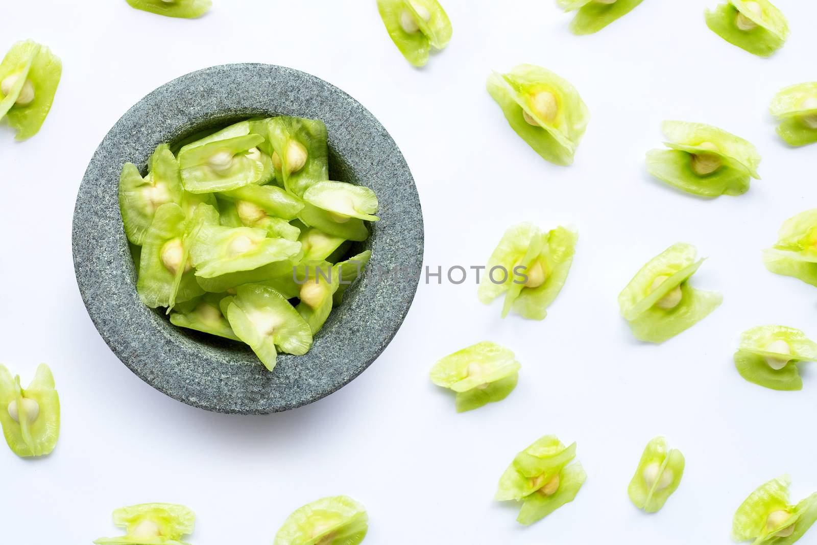 Moringa oleifera seeds in stone mortar on white background. 