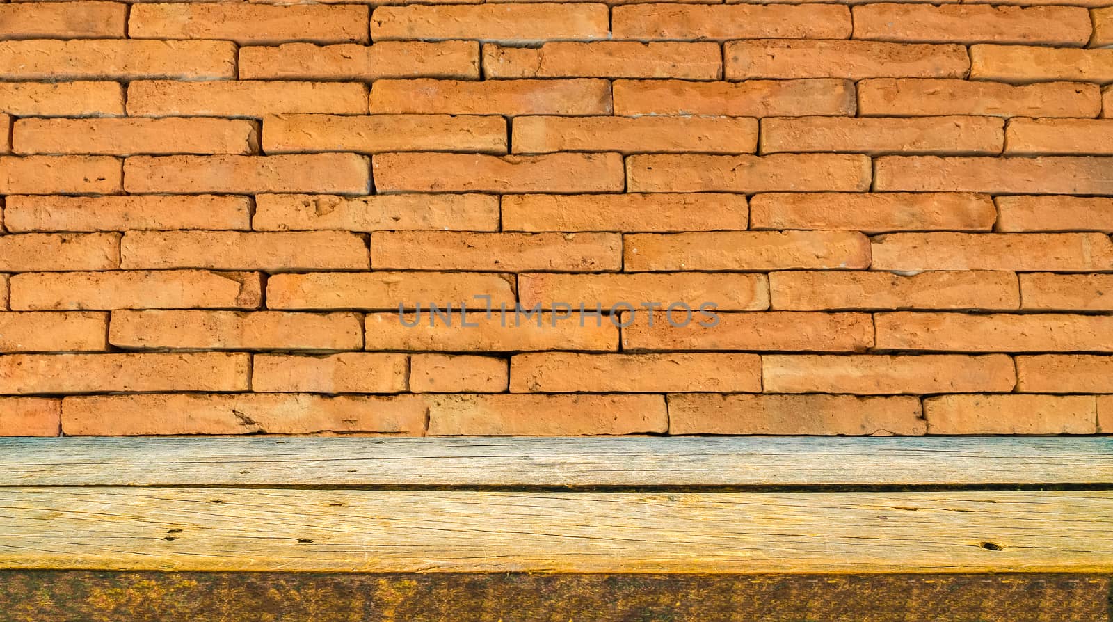 a natural wooden shelf in profile view with orange brick wall background
