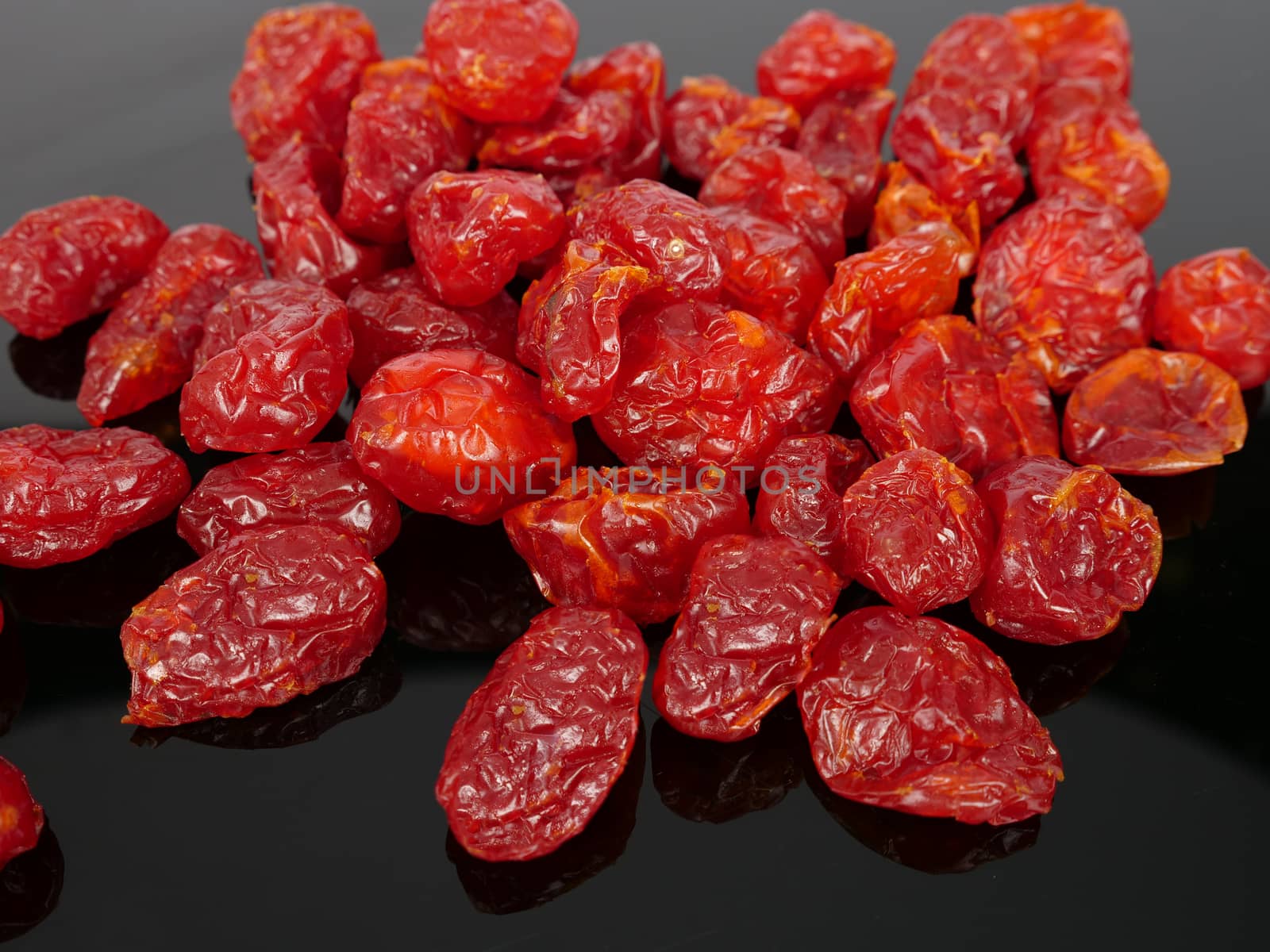 a heap of colorful dry cherry tomatoes on black background