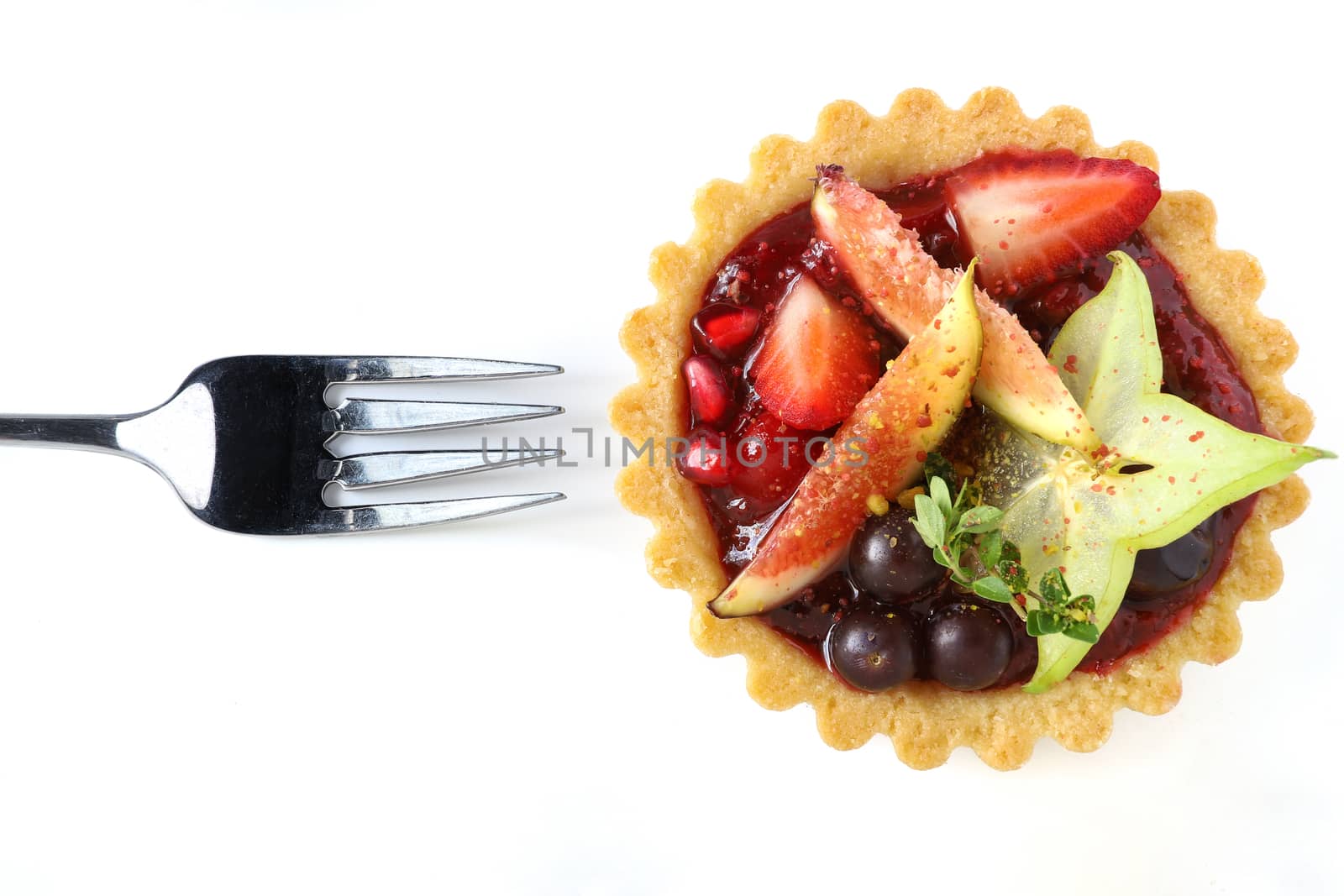 Mixed fruits tart with fig, pomegranate, starfruit, cherry, blueberry, grape, and raspberry jam. Isolated on white background, top view.