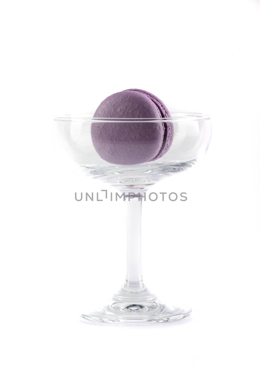 a purple macaroon with chocolate cream filling in a clear glass, isolated on white background