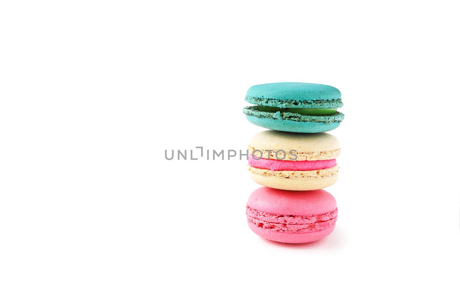 three pieces of macaroons with various colors and fillings on top of a table, isolated on white background