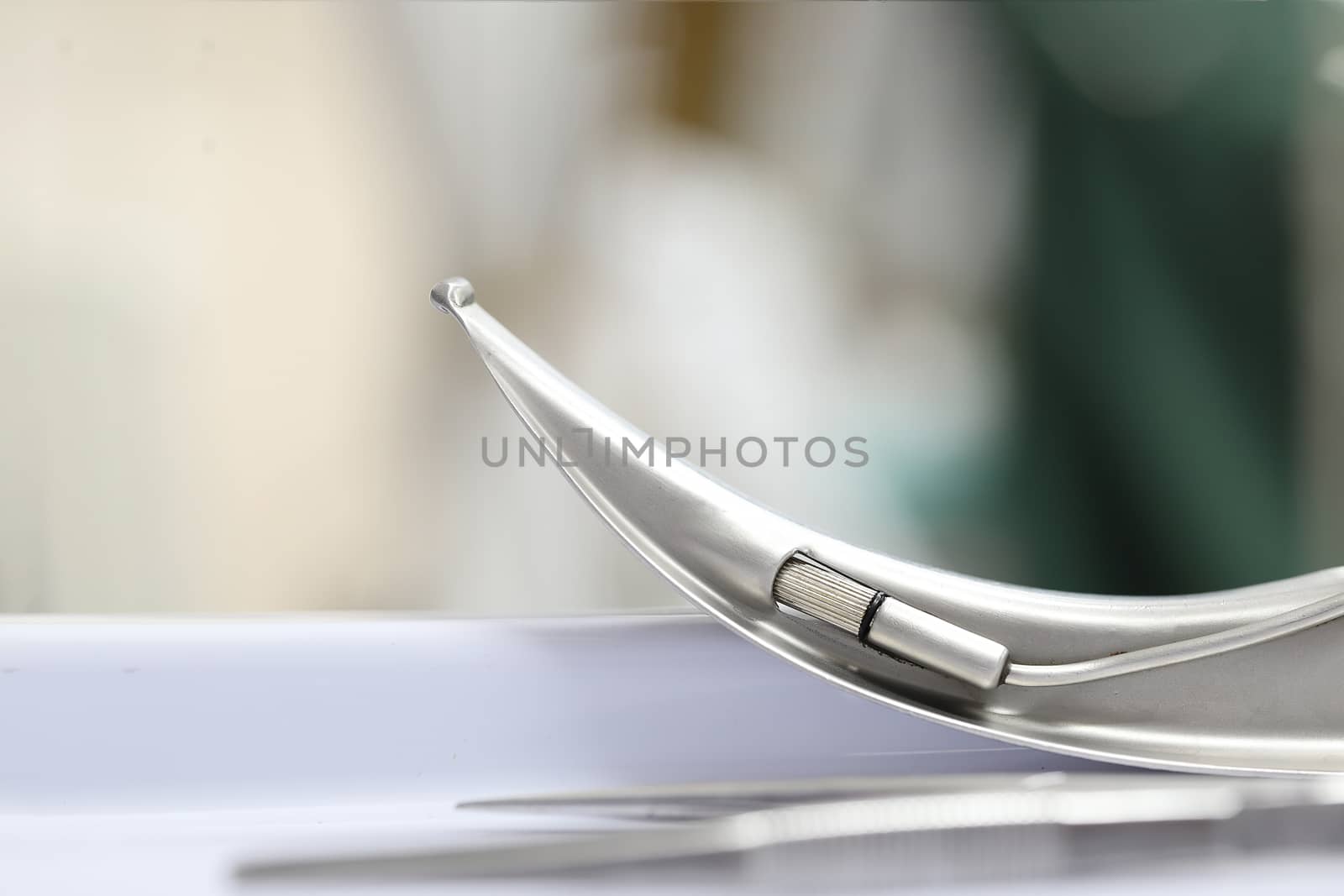 a tip of a laryngoscope blade on a table, isolated, blurred background