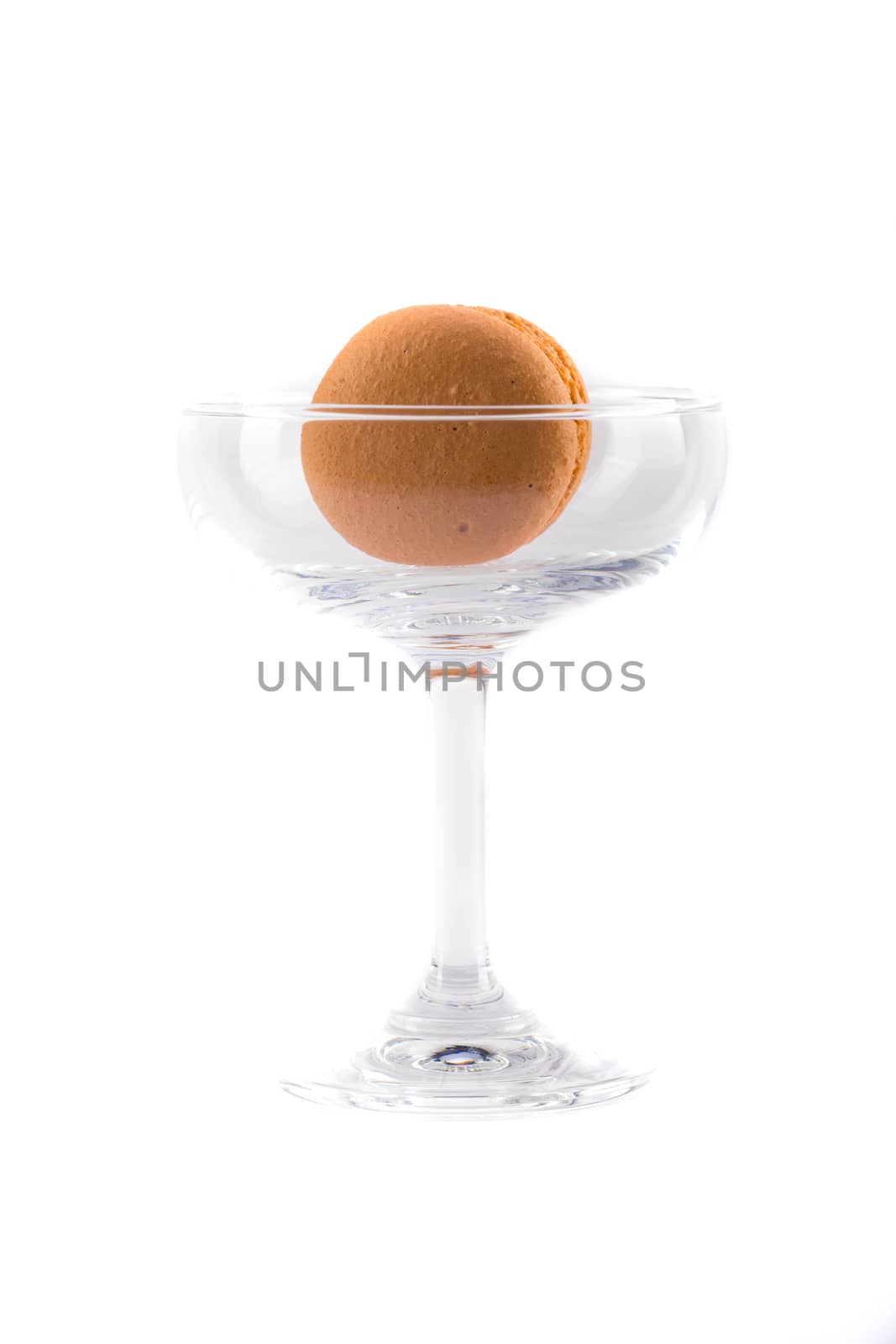 an orange flavored macaroon with orange jam filling in a clear glass, isolated on white background