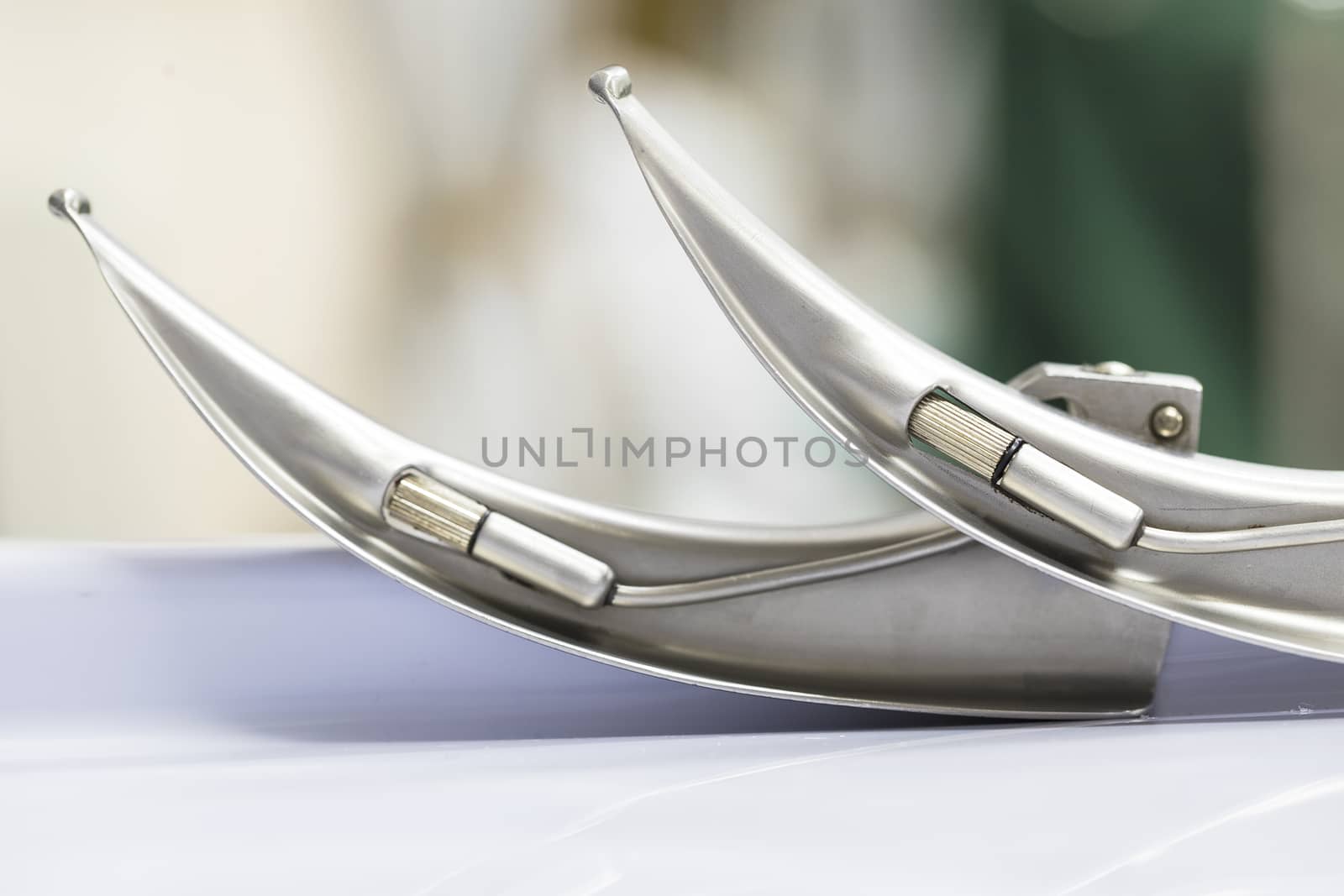 two shiny metal laryngoscope blades on a metal table top
