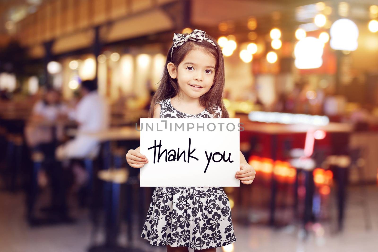 cute girl holding a piece of paper with the words Thank You , blur restaurant background