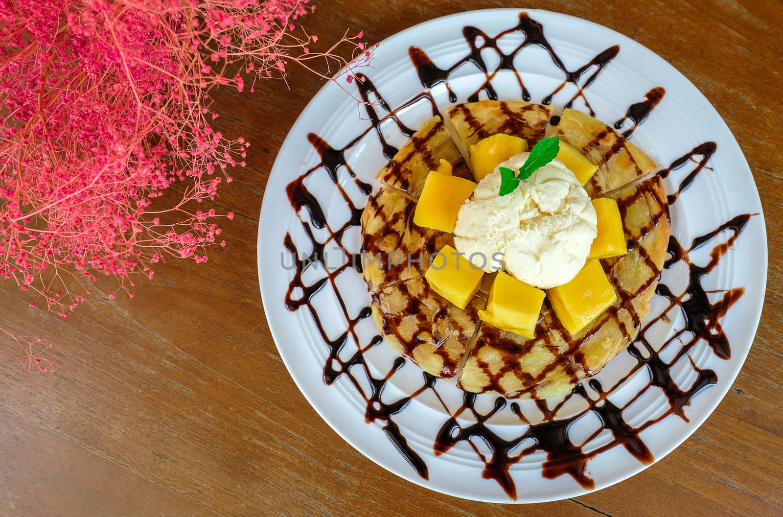 indian style roti with vanilla ice cream and cubes of ripe mango and chocolate sauce, top view, directly above