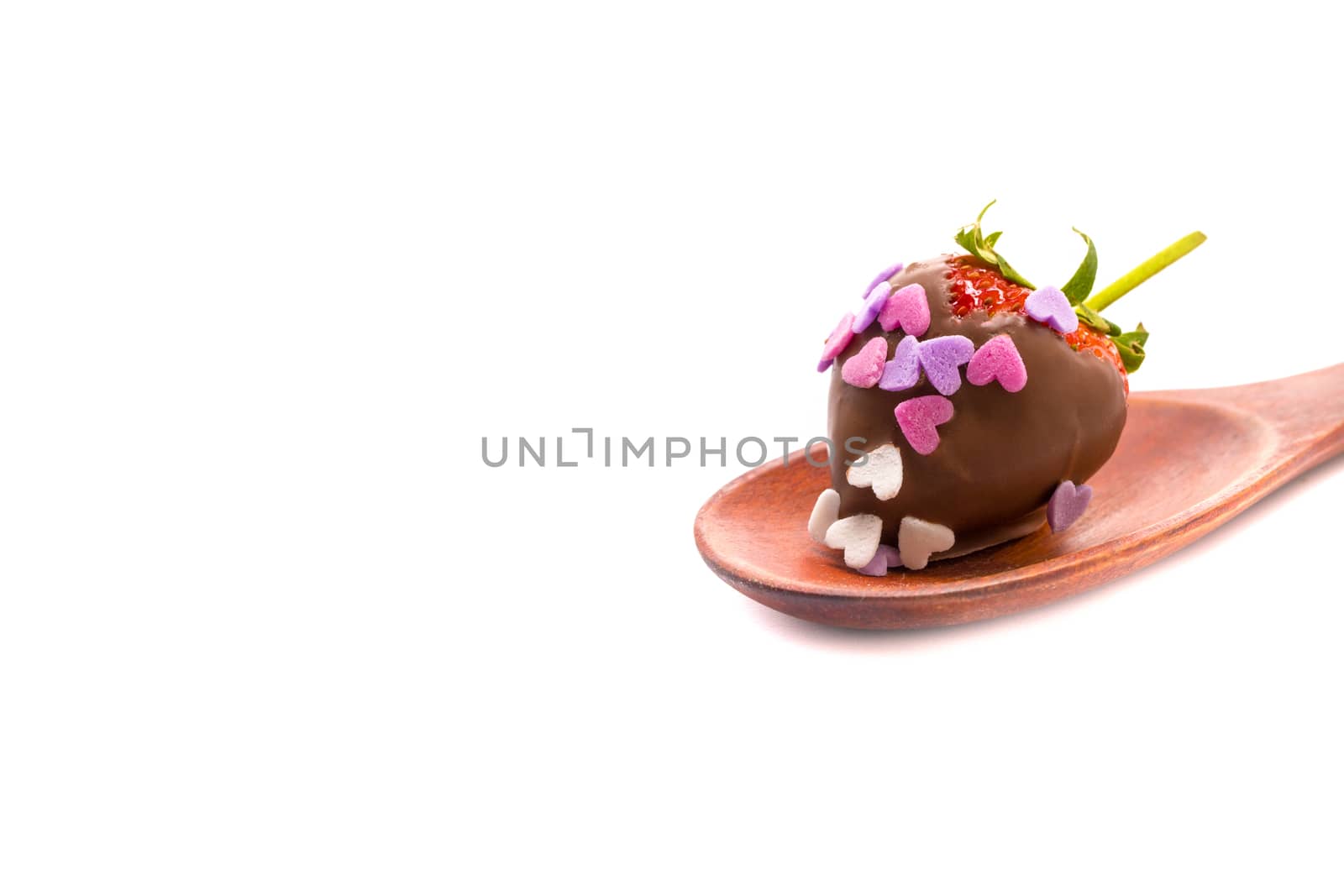 a chocolate coated strawberry with small heart-shape sugar confetti, on a brown wooden spoon, isolated on white background, Valentine
