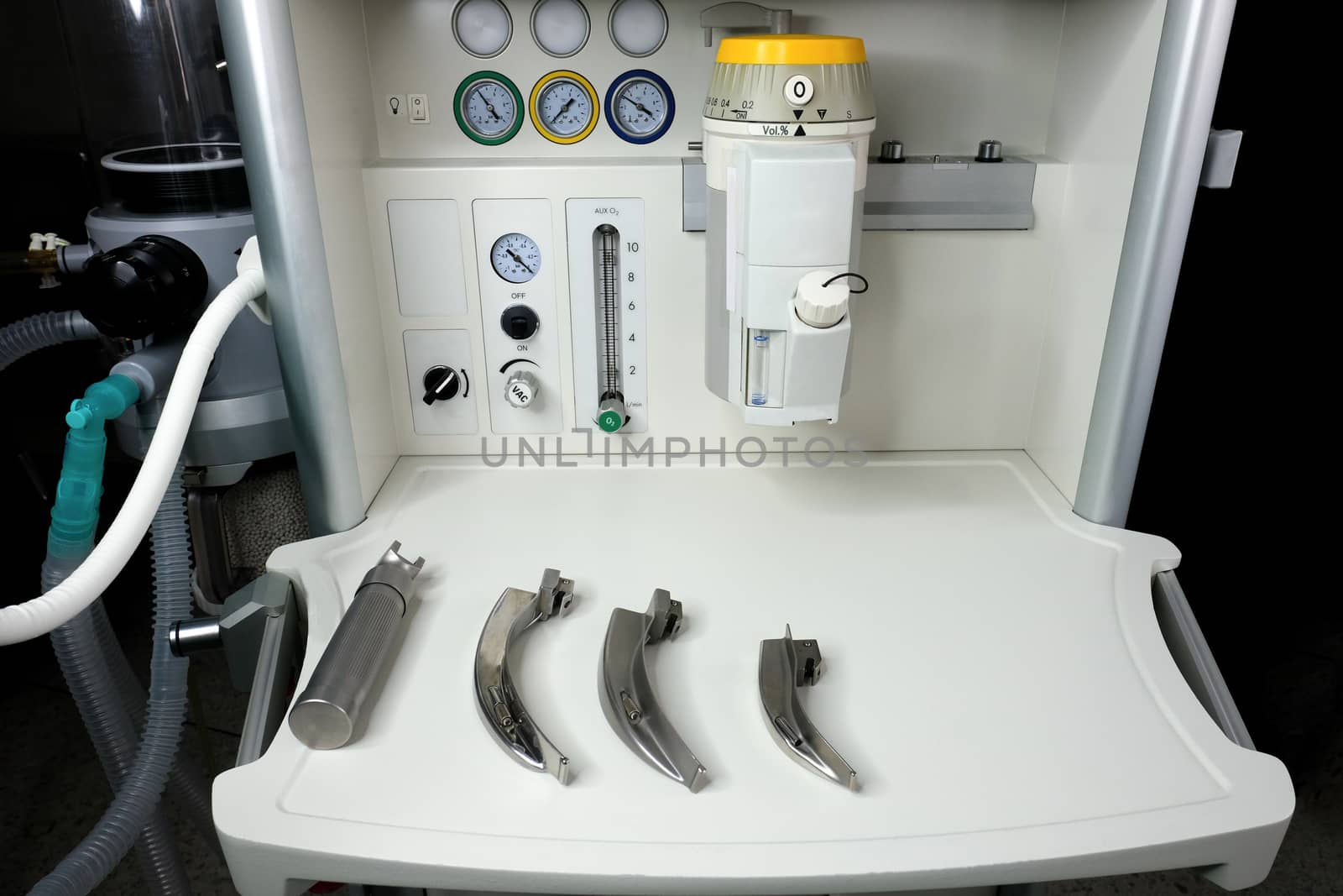 an anesthetic machine in the operation room with a set of laryngoscope and blades ready for intubation